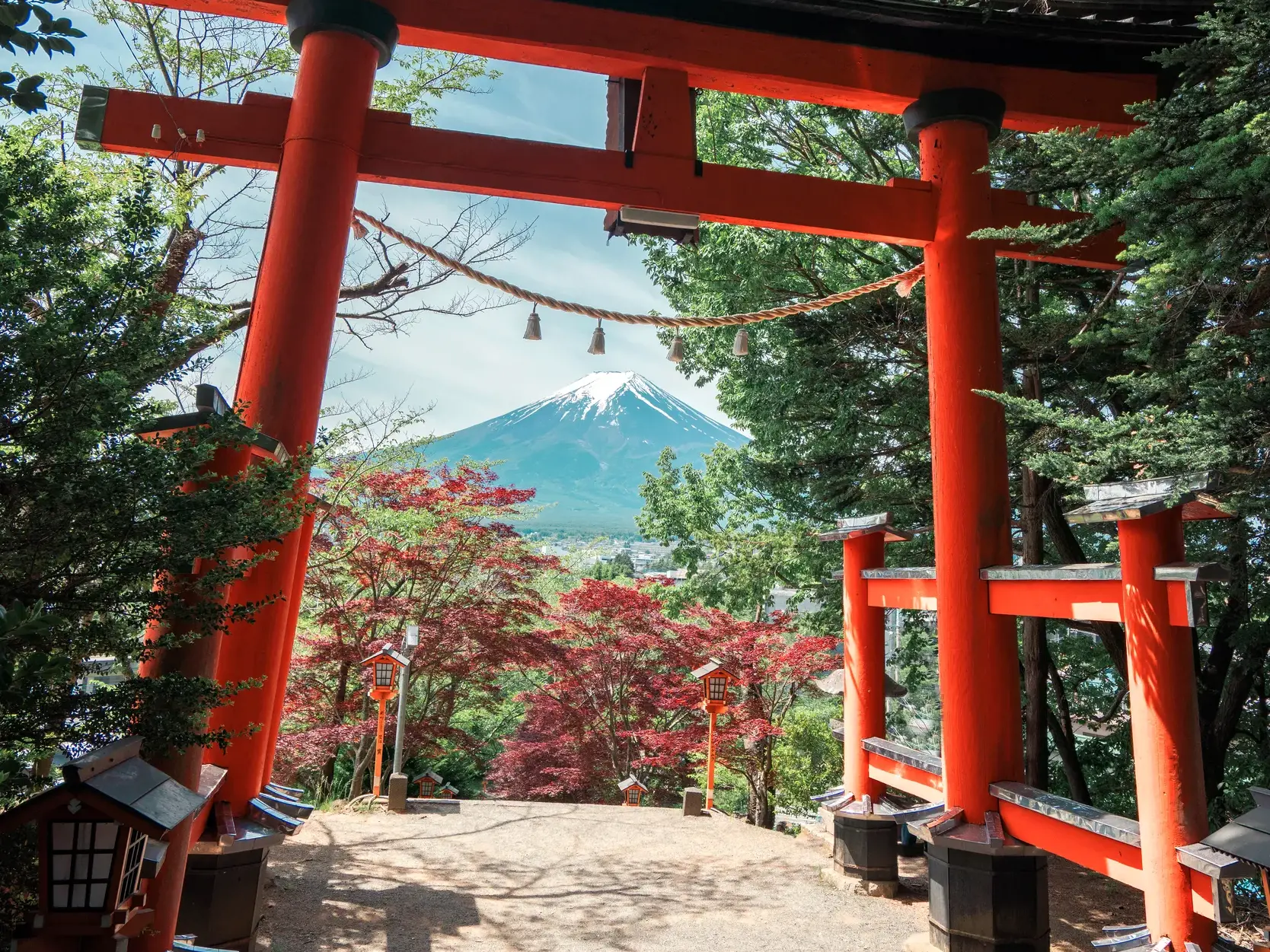 Ein großes, rotes Torii-Tor rahmt den malerischen Blick auf den schneebedeckten Gipfel des heiligen Berges Fuji-san.