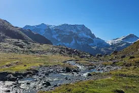 Klarer Bergbach auf einer Wanderung in den Graubündner Alpen mit Blick auf schneebedeckte Gipfel bei Bivio.