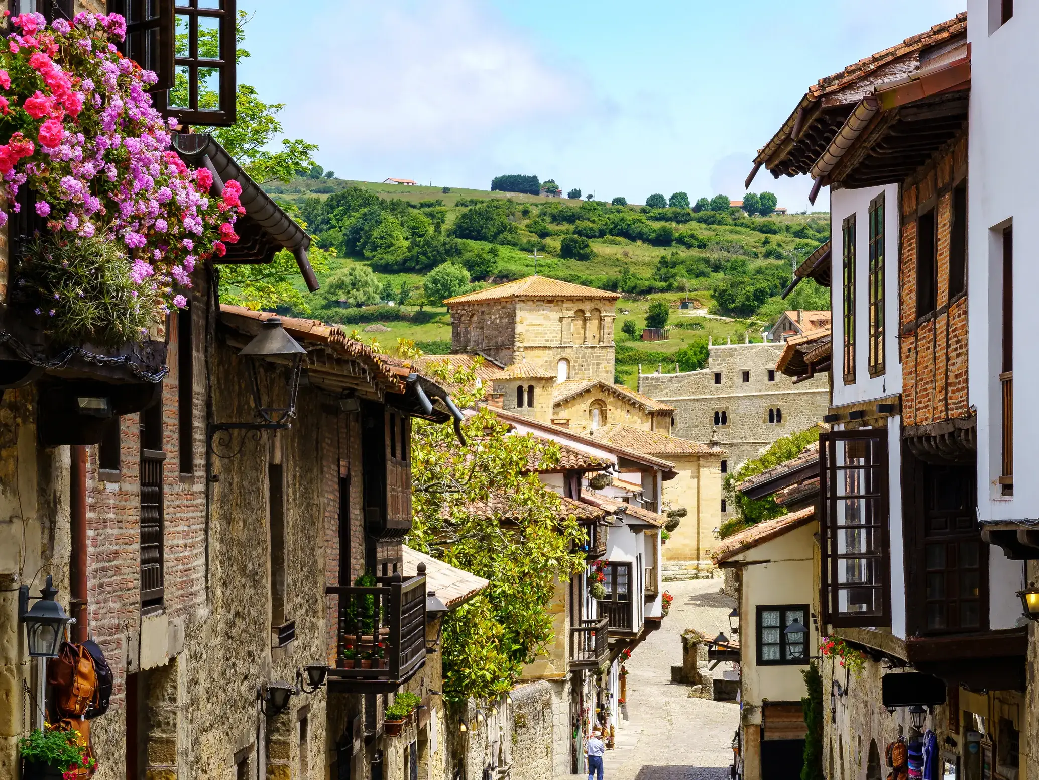 Blick durch eine enge Gasse mit blumengeschmückten Balkonen in der historischen Altstadt von Santillana del Mar in Kantabrien.