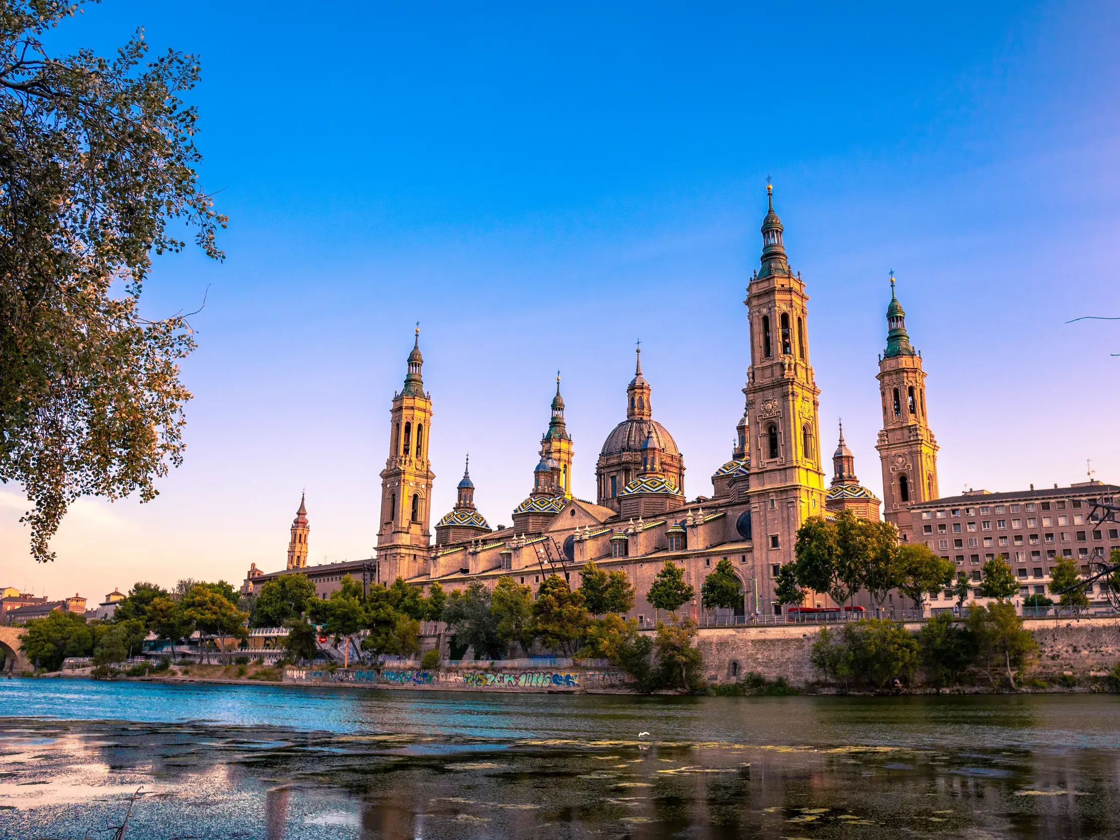 Die barocke Basilika Nuestra Señora del Pilar in Saragossa thront am Ufer des Ebro im goldenen Abendlicht.