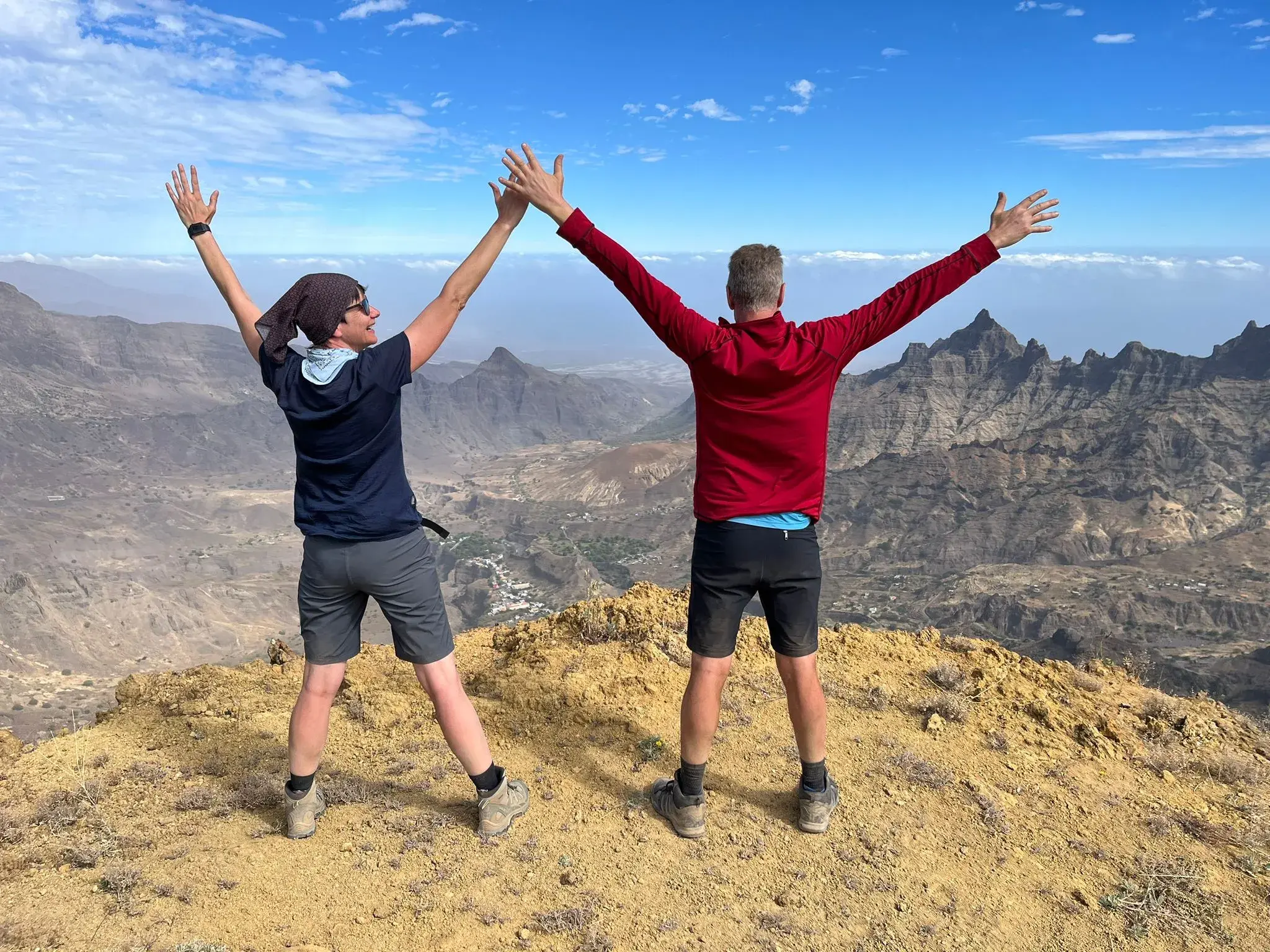 Zwei Wanderer feiern mit erhobenen Armen ihren Gipfelerfolg beim Trekking auf der kapverdischen Insel Santo Antão.