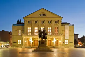 Das beleuchtete Nationaltheater in Weimar mit dem Goethe- und Schiller-Denkmal auf dem Theaterplatz am Abend