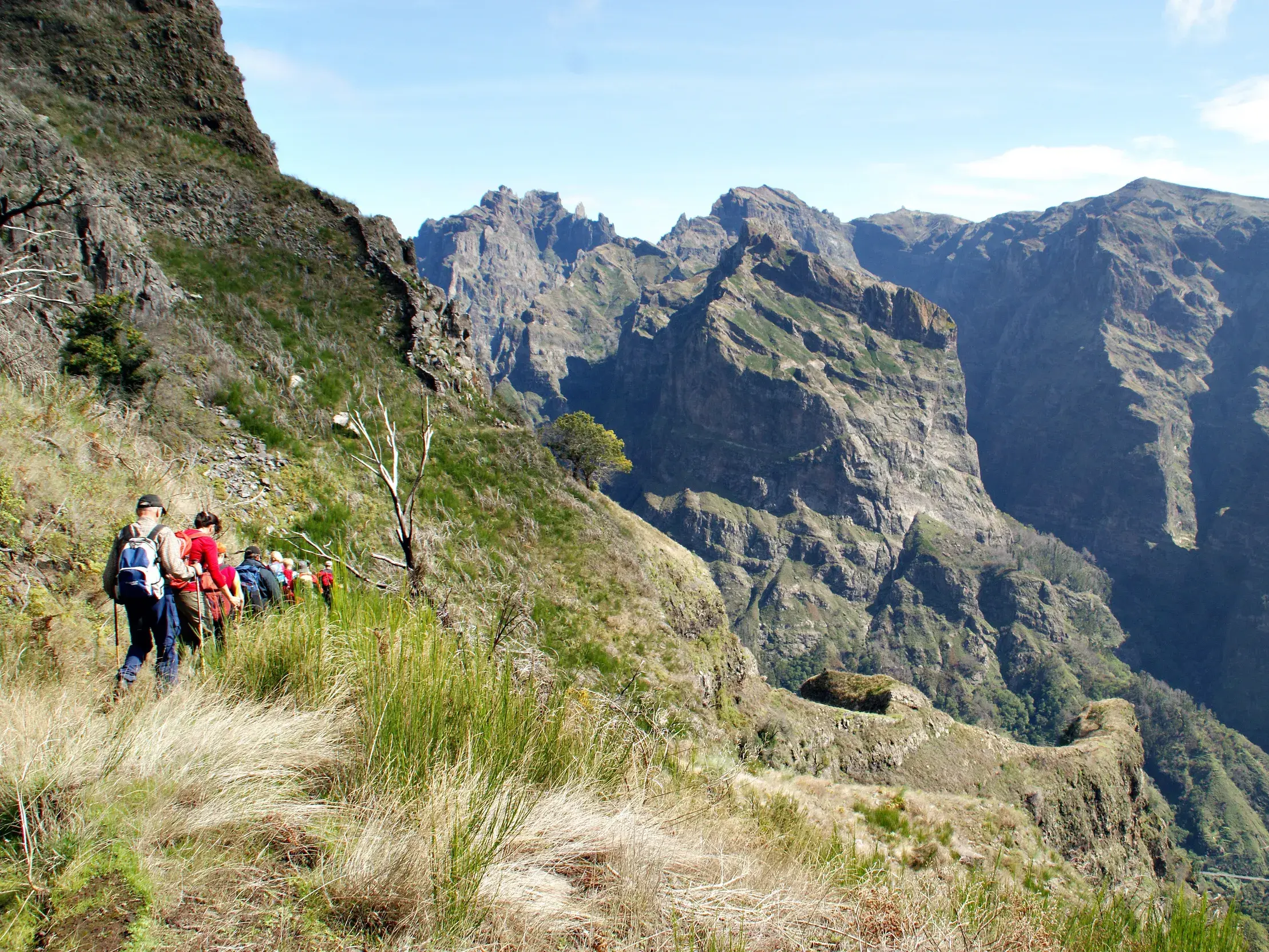 Hauser Reisegruppe bei der Wanderung zum Pico Grande auf einem schmalen Bergpfad mit Blick auf das Zentralmassiv von Madeira.