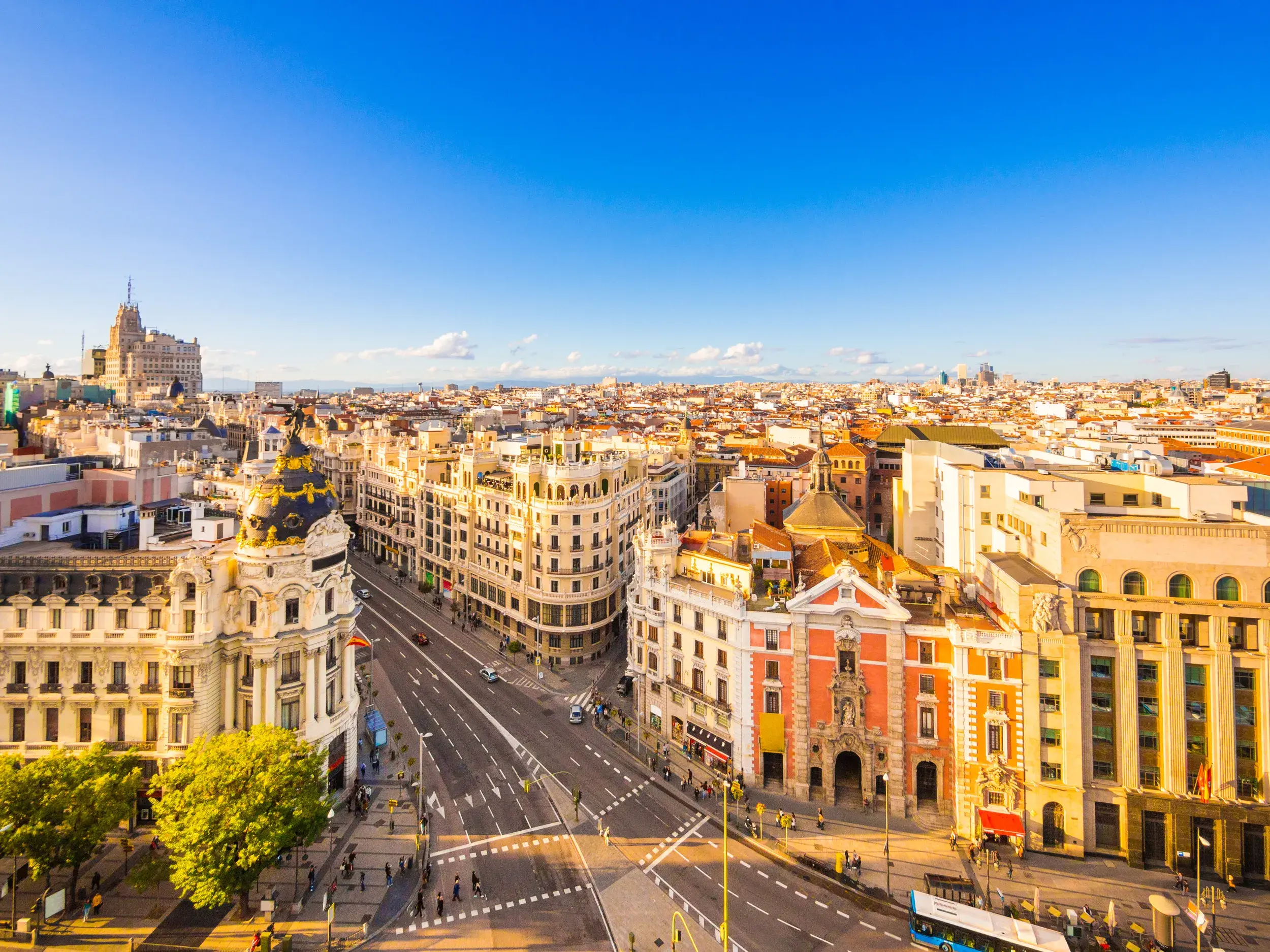 Weitblick über die Dächer Madrids bei Sonnenschein, im Vordergrund das prachtvolle Metrópolis-Gebäude an der Gran Vía.