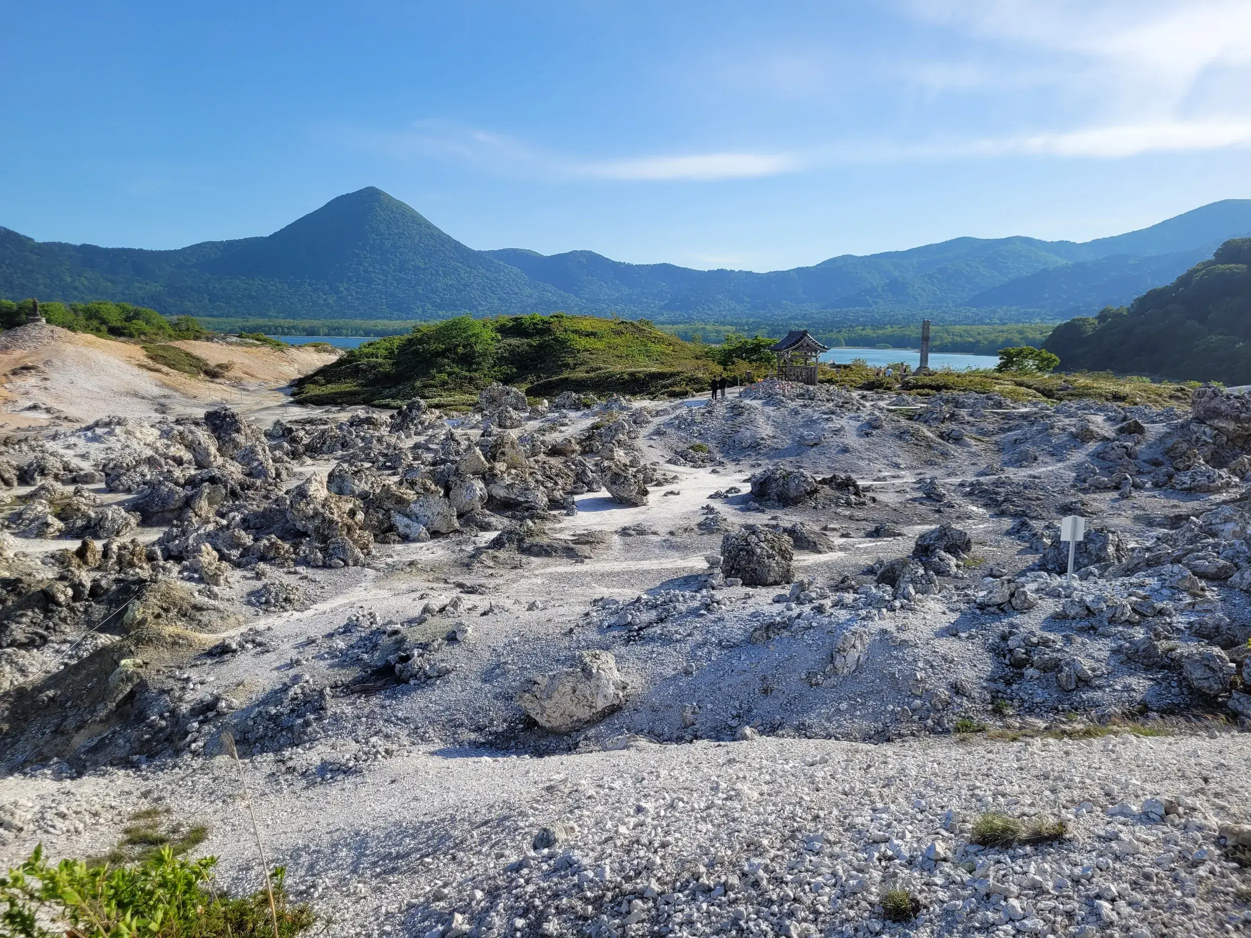 Karge Schwefellandschaft am heiligen Berg Osorezan auf Honshu, dem japanischen 'Tor zur Unterwelt' mit See im Hintergrund.