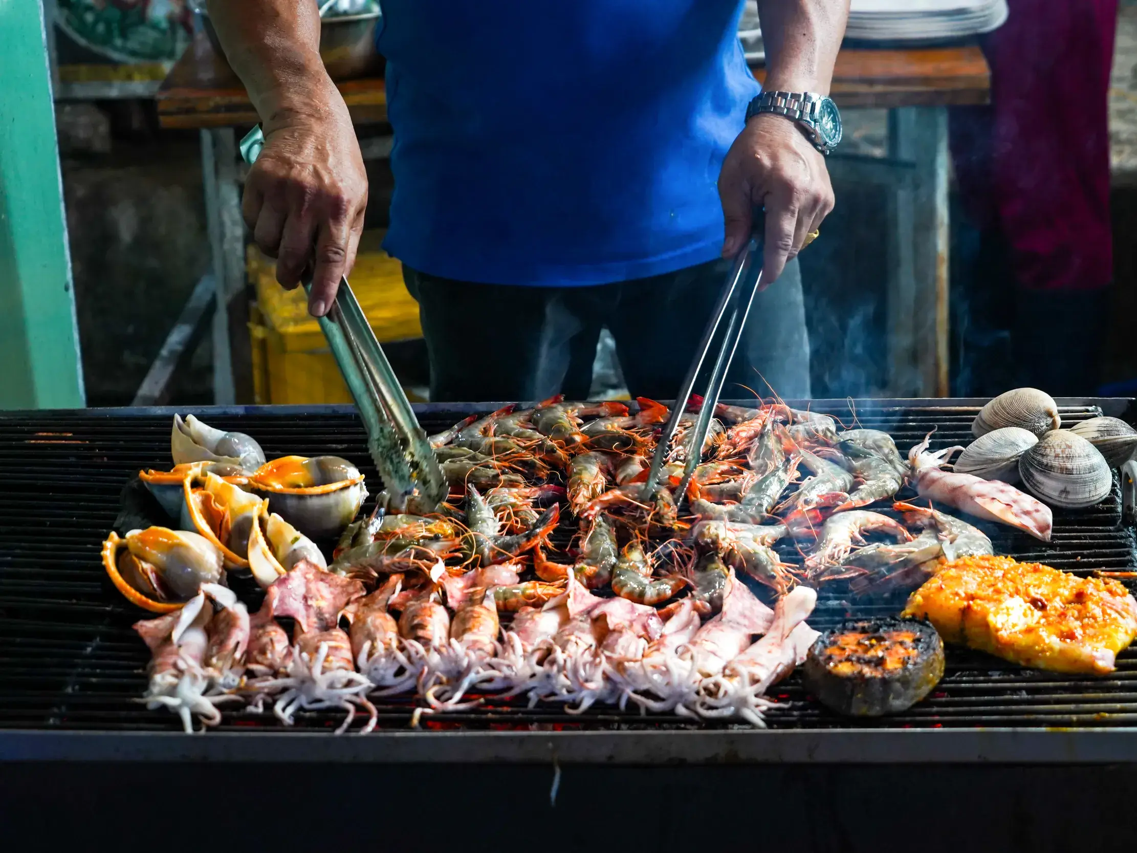 Frische Meeresfrüchte wie Garnelen, Tintenfische und Muscheln brutzeln auf dem Grill eines Streetfood-Stands in Kambodscha.