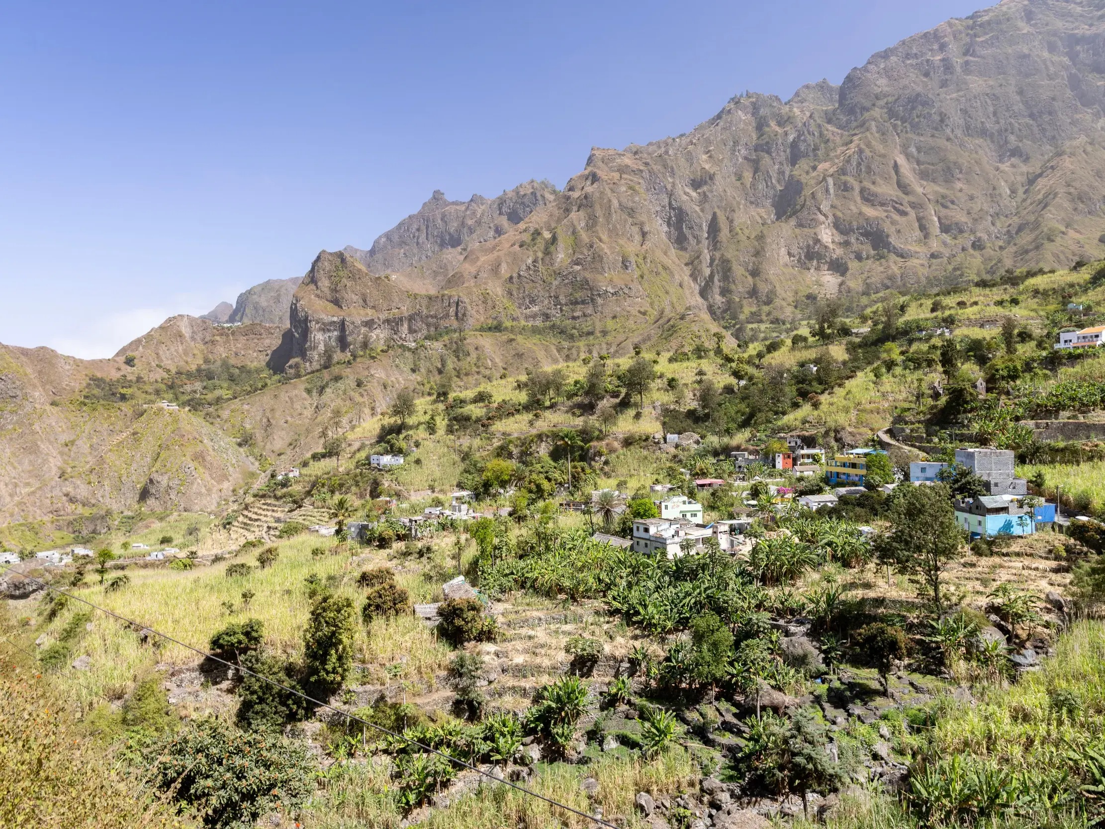 Blick auf ein Bergdorf mit terrassierten Feldern im fruchtbaren Paúl-Tal vor der schroffen Bergkulisse von Santo Antão.