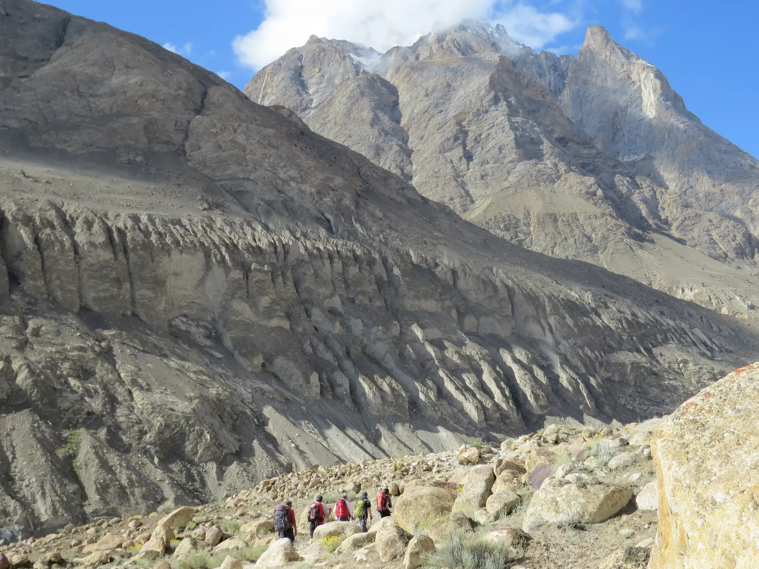 Eine Trekkinggruppe wandert auf einem steinigen Pfad durch die karge, beeindruckende Gebirgslandschaft des Karakorum in Pakistan.