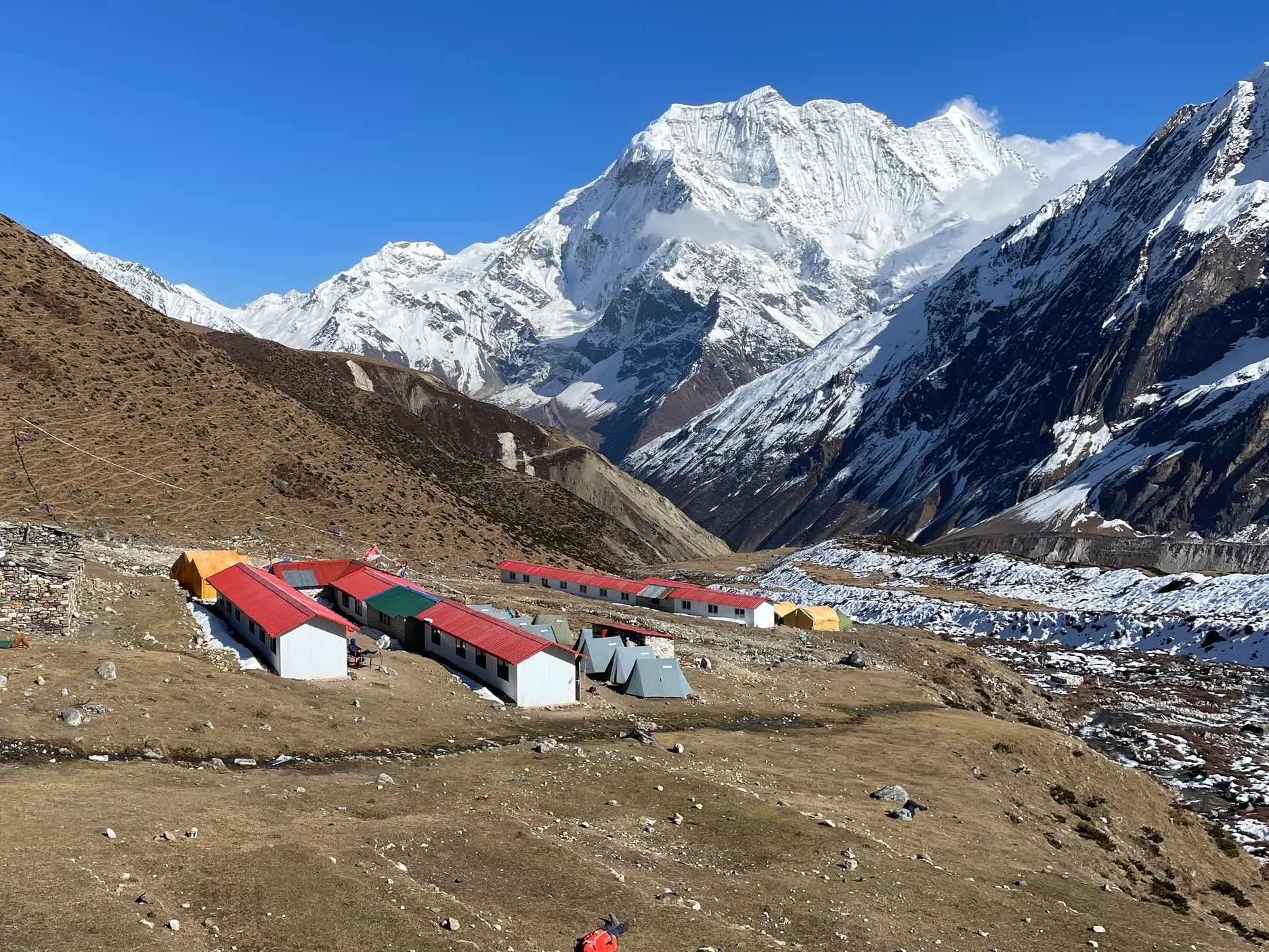 Einfache Lodges der Siedlung Dharamsala im nepalesischen Himalaya vor dem gewaltigen, schneebedeckten Manaslu-Massiv.