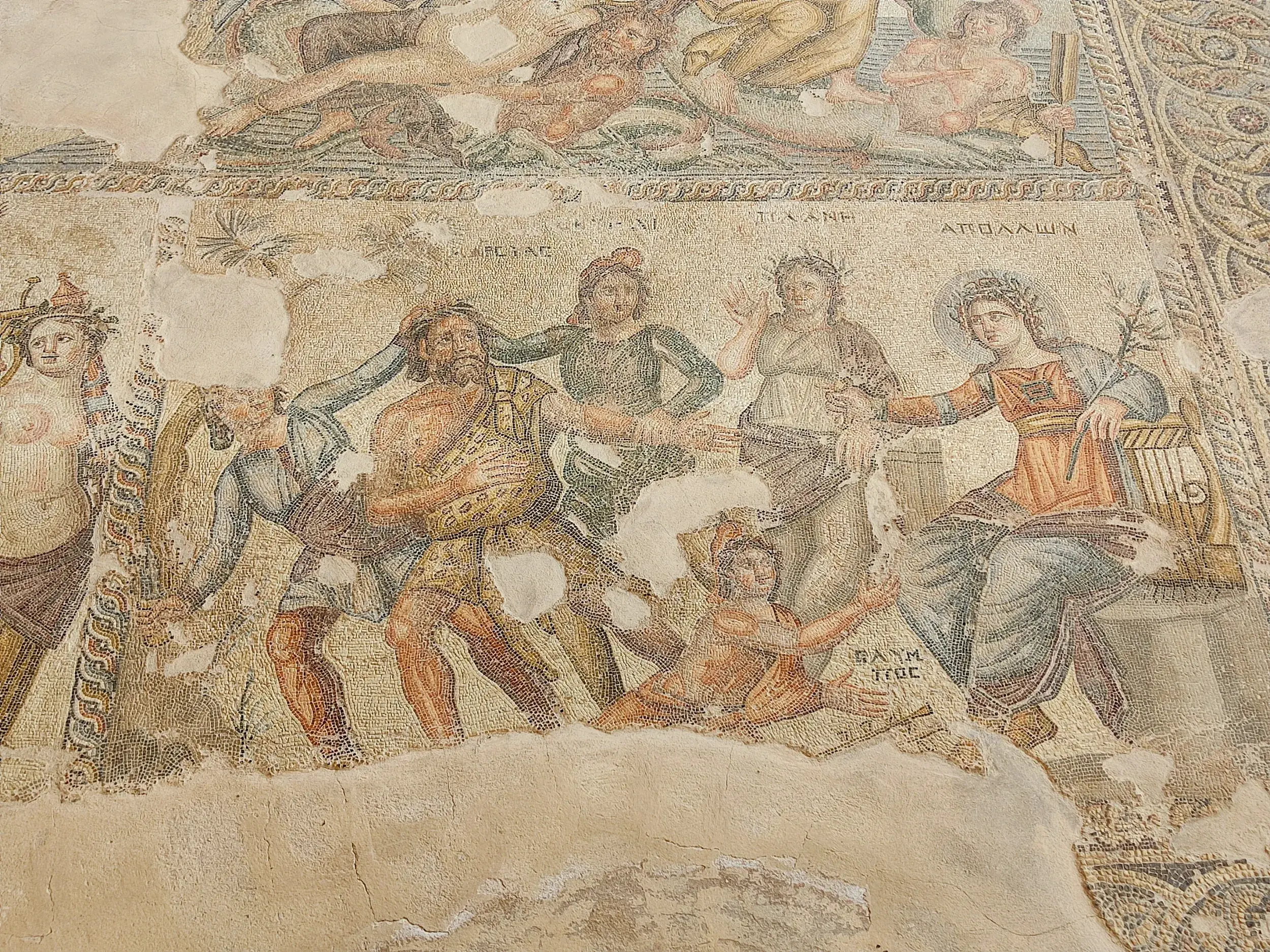 Nahaufnahme eines antiken, teils beschädigten Bodenmosaiks in Paphos mit Darstellung griechischer Götter wie Apollo mit Leier.