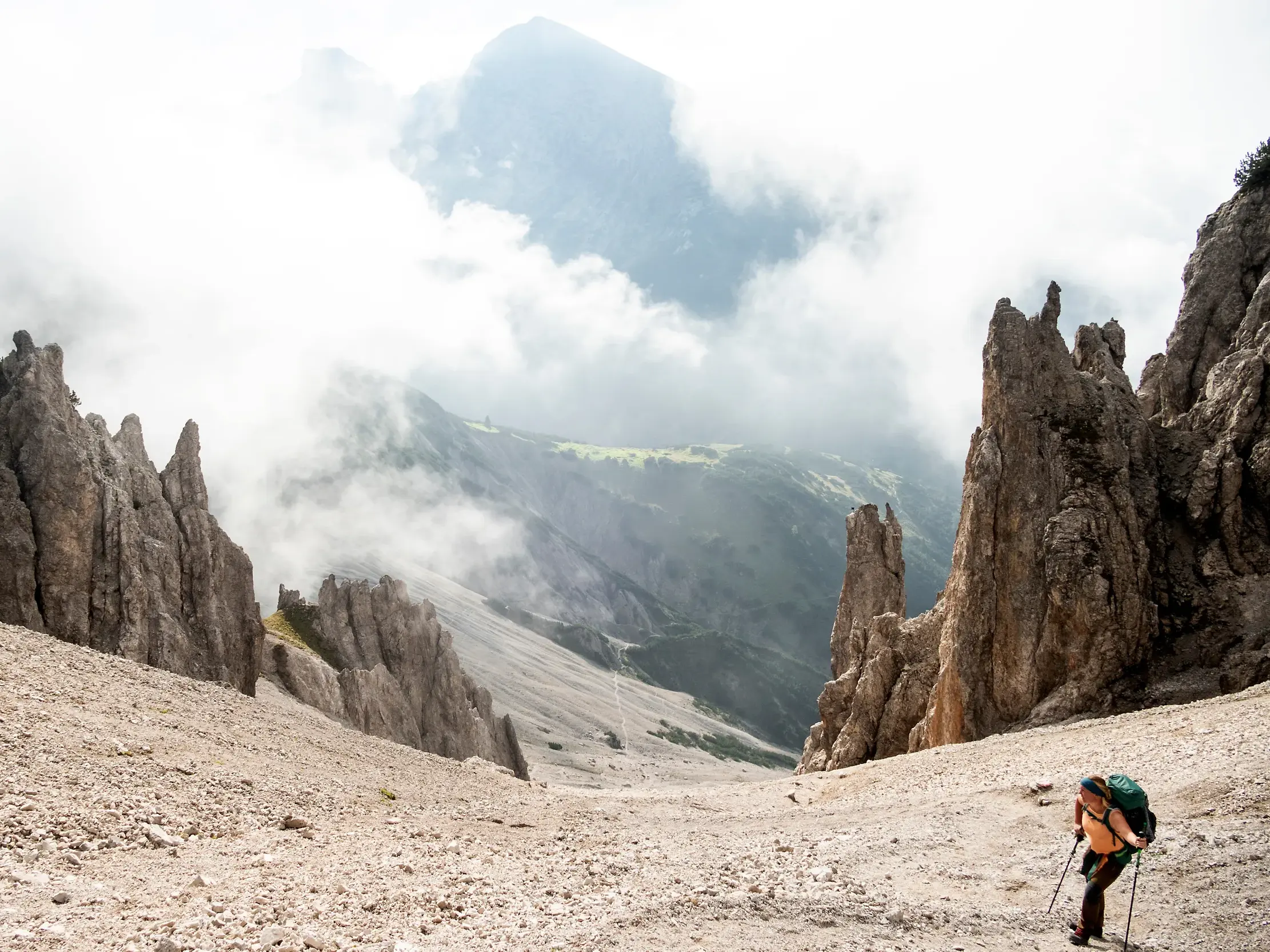 Eine Wanderin steigt auf einem Geröllfeld durch die schroffen Felsen der Erlspitzgruppe zur Eppzirler Scharte im Karwendel auf.