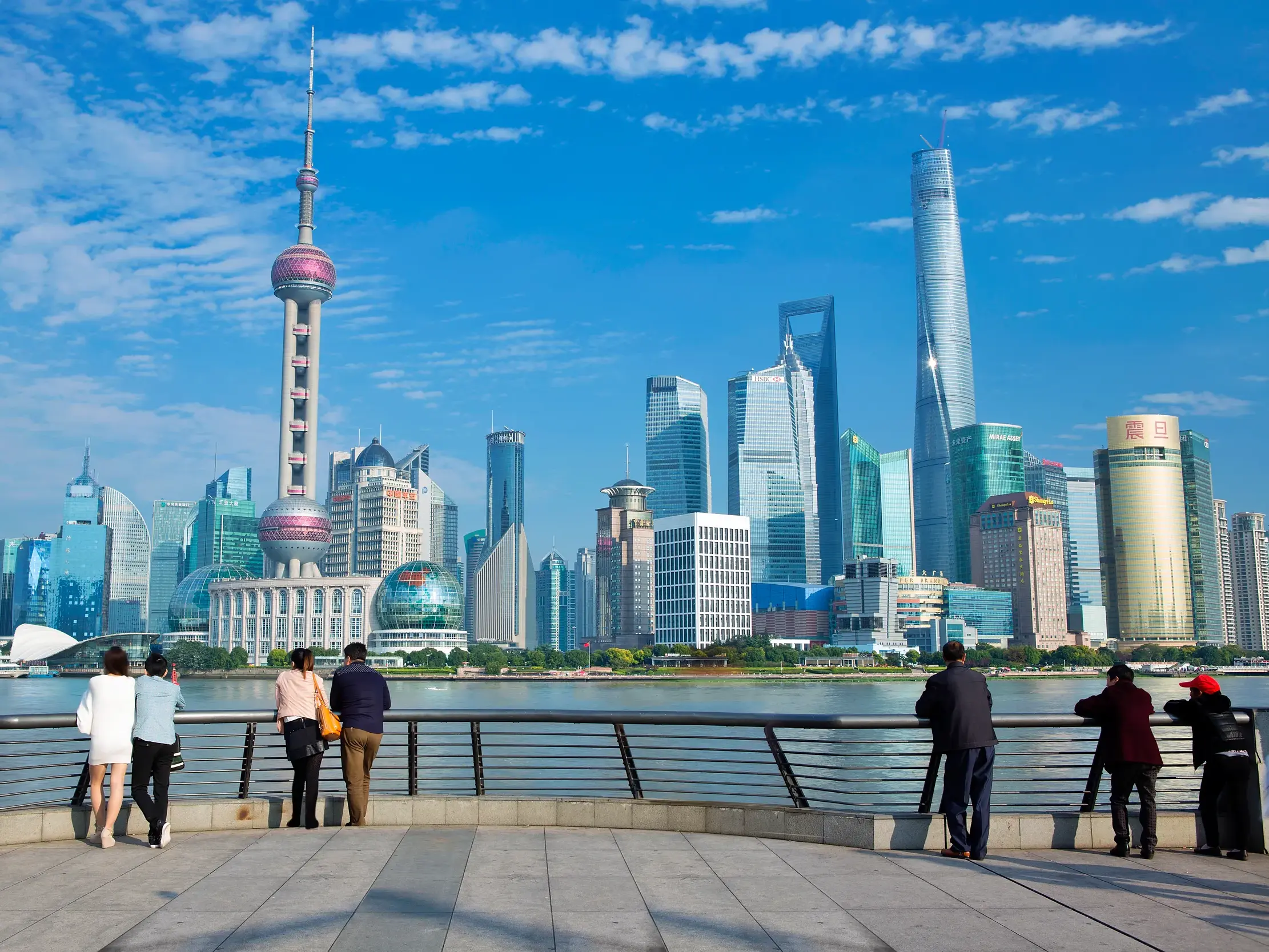 Blick von der Uferpromenade Bund auf die moderne Skyline von Pudong in Shanghai bei strahlendem Sonnenschein.