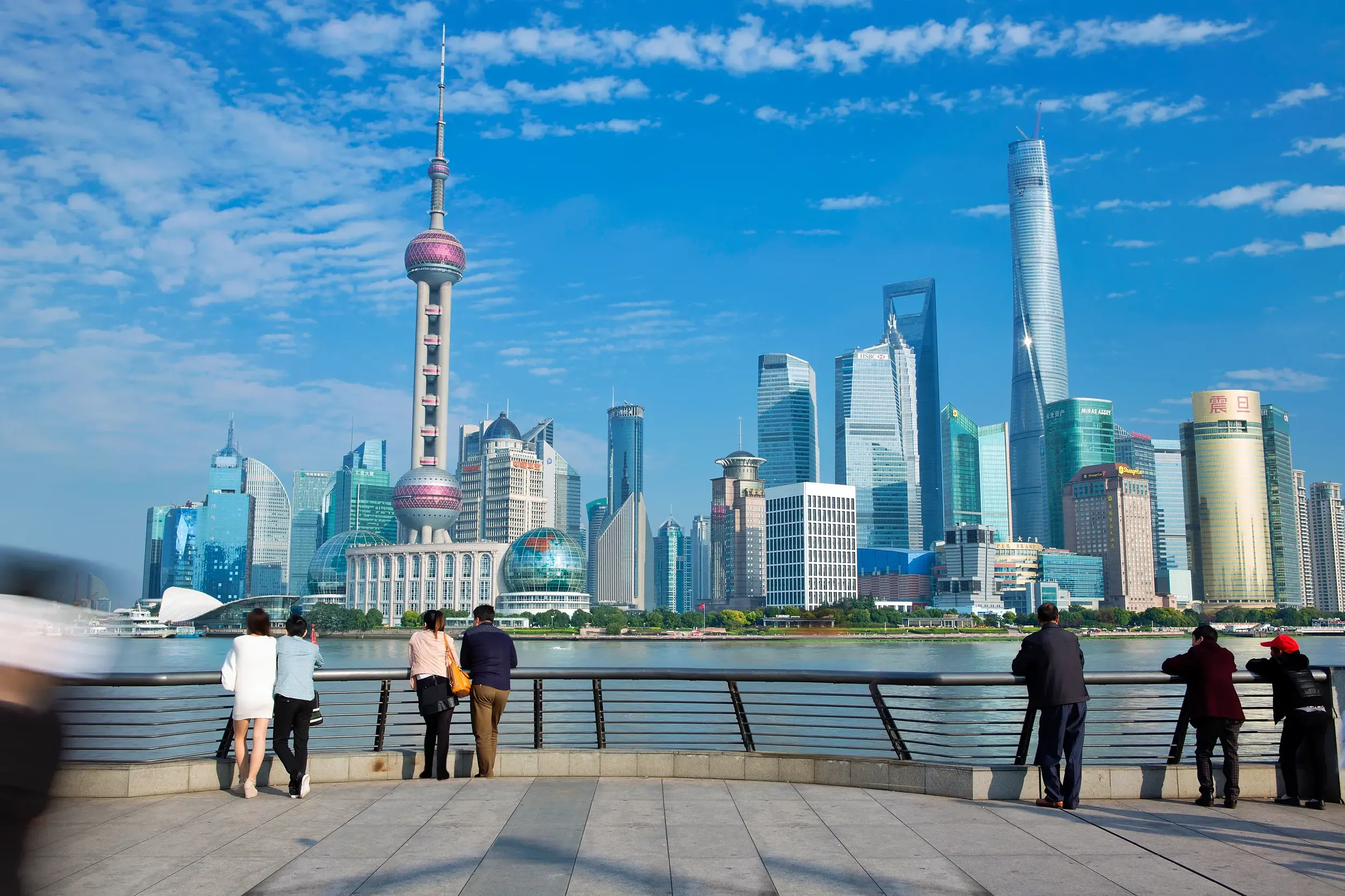 Blick von der Uferpromenade Bund auf die moderne Skyline von Pudong in Shanghai bei strahlendem Sonnenschein.