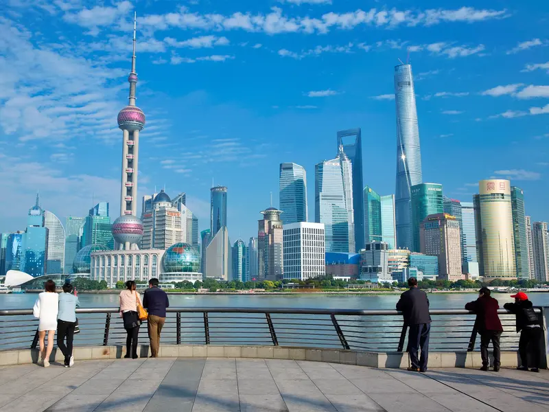 Blick von der Uferpromenade Bund auf die moderne Skyline von Pudong in Shanghai bei strahlendem Sonnenschein.