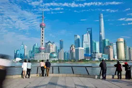 Blick von der Uferpromenade Bund auf die moderne Skyline von Pudong in Shanghai bei strahlendem Sonnenschein.