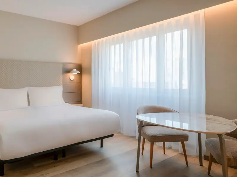 Helles Doppelzimmer im Hotel AC Carlton auf einer Singlereise nach Madrid mit Bett und Sitzecke.