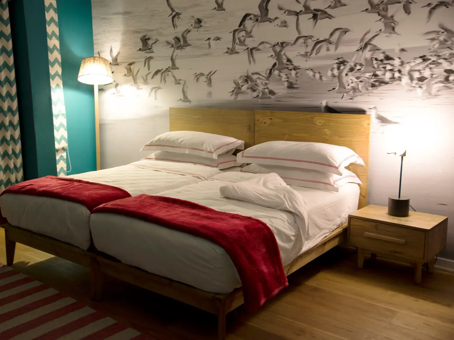 Modern eingerichtetes Zimmer im Guesthouse in Swakopmund mit zwei Betten und einer großen Fototapete mit Küstenvögeln.