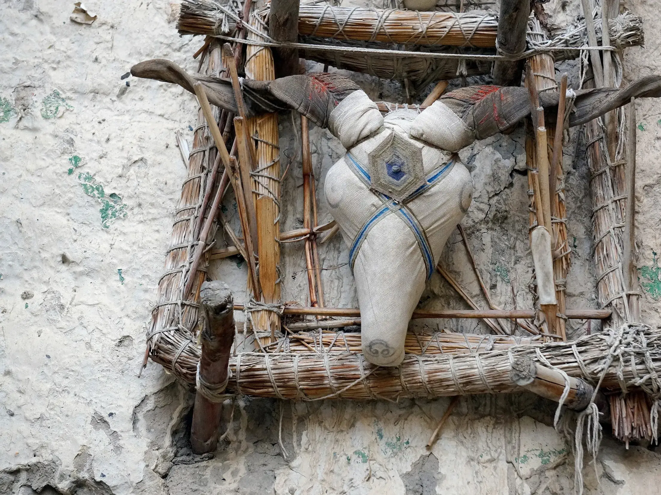 Traditionelle Geisterfalle als Tierkopf aus Stoff und Holz an einer verwitterten Hauswand in einem Dorf in Mustang, Nepal.