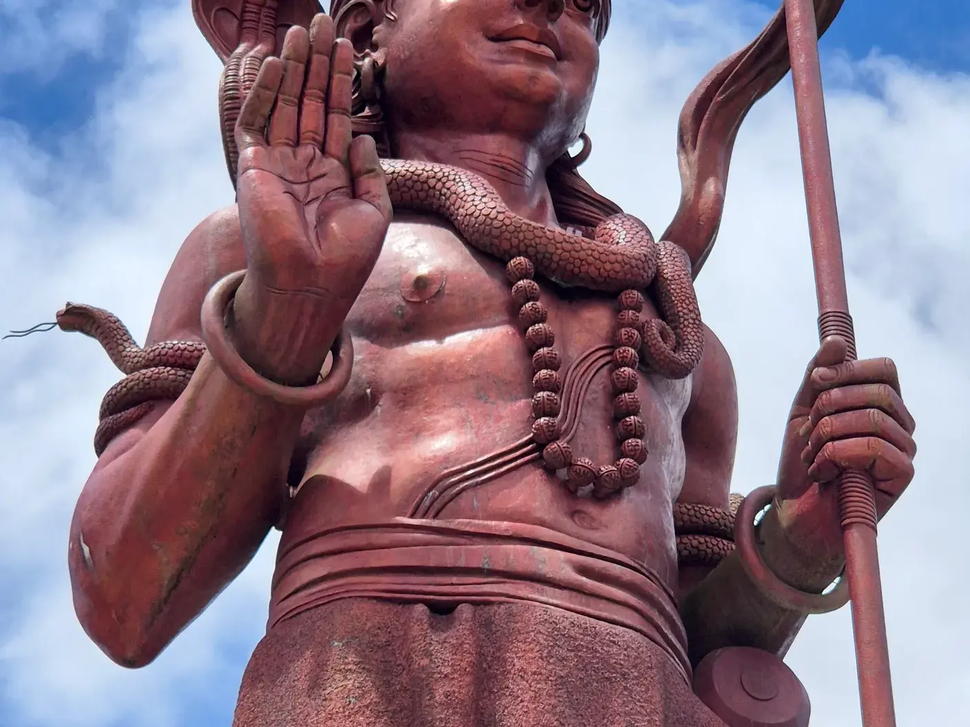 Rote Statue des Hindu-Gottes Shiva mit erhobener Hand und Schlange am heiligen See Grand Bassin auf Mauritius.