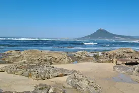 Küstenwanderung am Jakobsweg in Portugal: felsiger Strand mit Blick auf den Monte de Santa Luzia bei Vila Praia de Ancora.