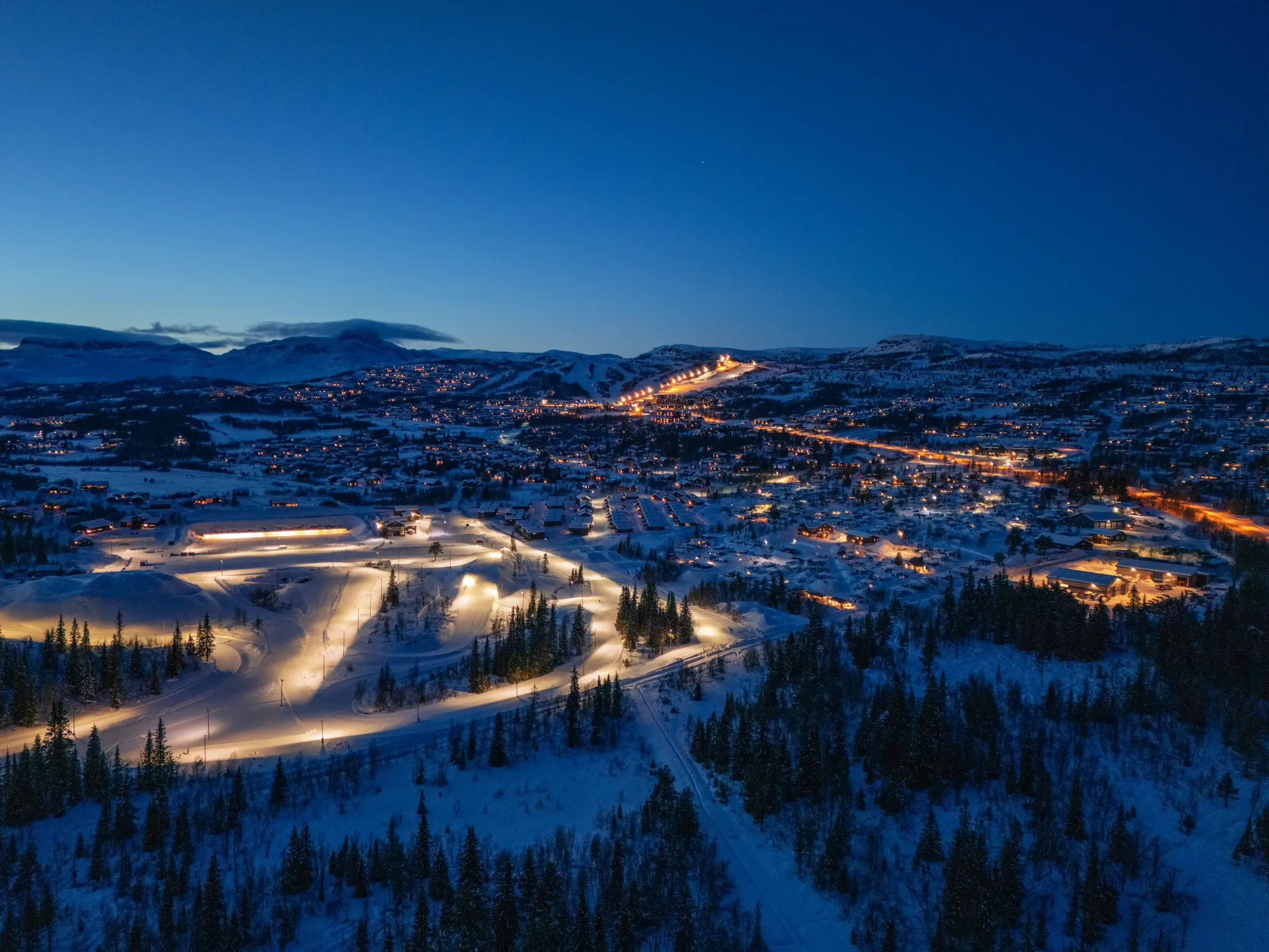 Abendlicher Blick über das beleuchtete Skidorf Beitostølen mit Loipen im norwegischen Winterparadies Valdres.