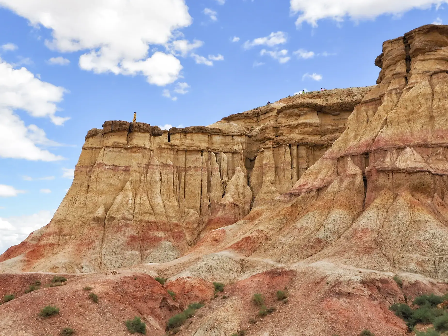 Wanderer blickt von den rot-ockerfarbenen 'glühenden Klippen' in Bayanzag über die Weite der mongolischen Wüste Gobi.