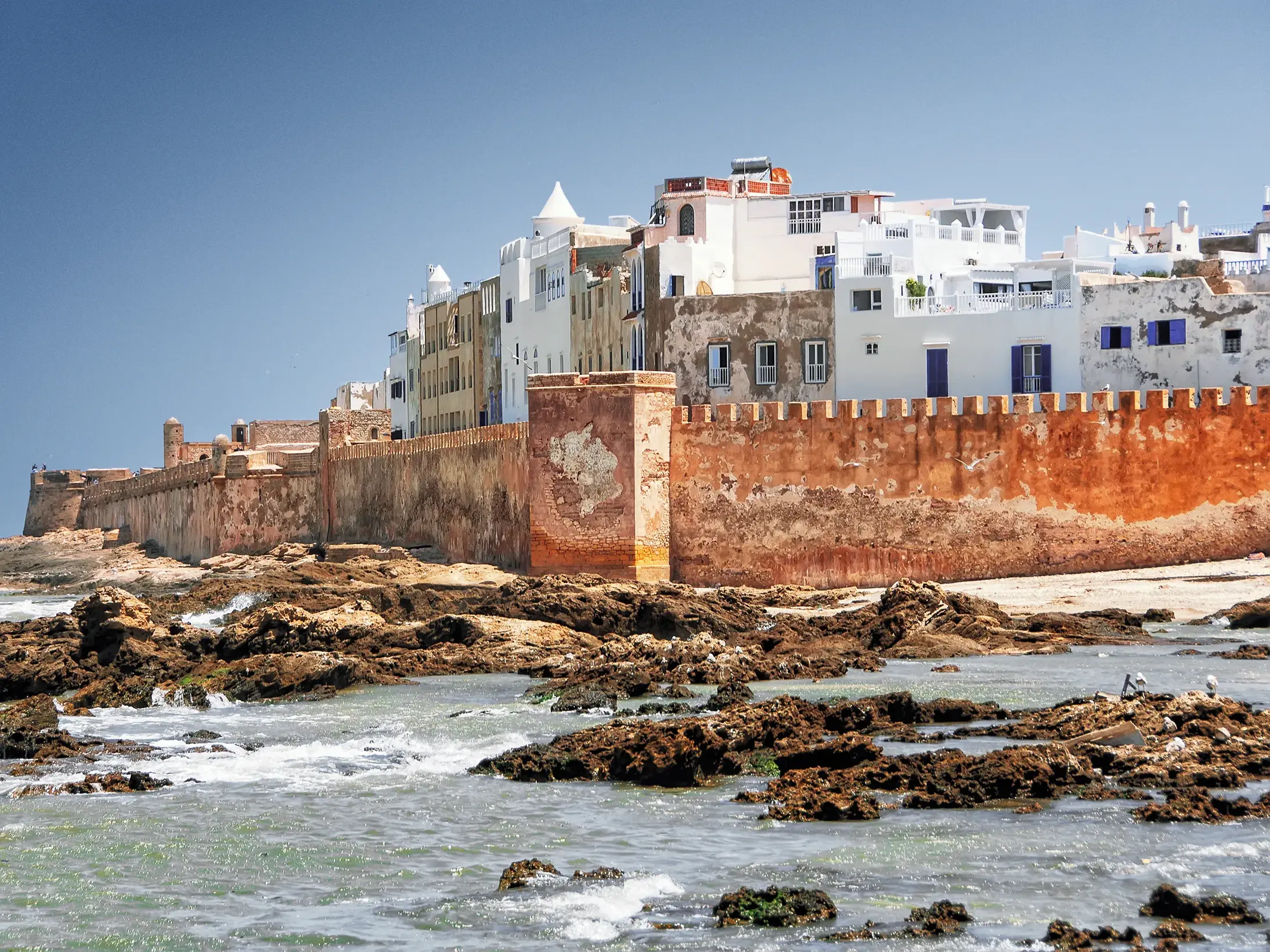Die beeindruckende rote Stadtmauer von Essaouira schützt die weiße Medina vor den Wellen des Atlantiks in Marokko.