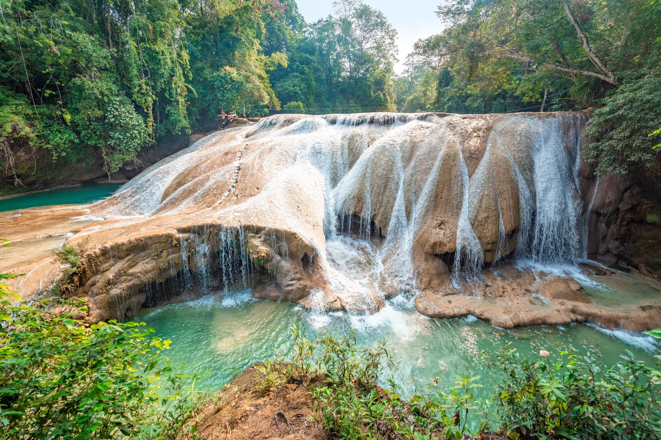 Breite Kaskaden der Wasserfälle von Roberto Barrios stürzen in türkise Naturpools, umgeben von dichtem Regenwald in Mexiko.