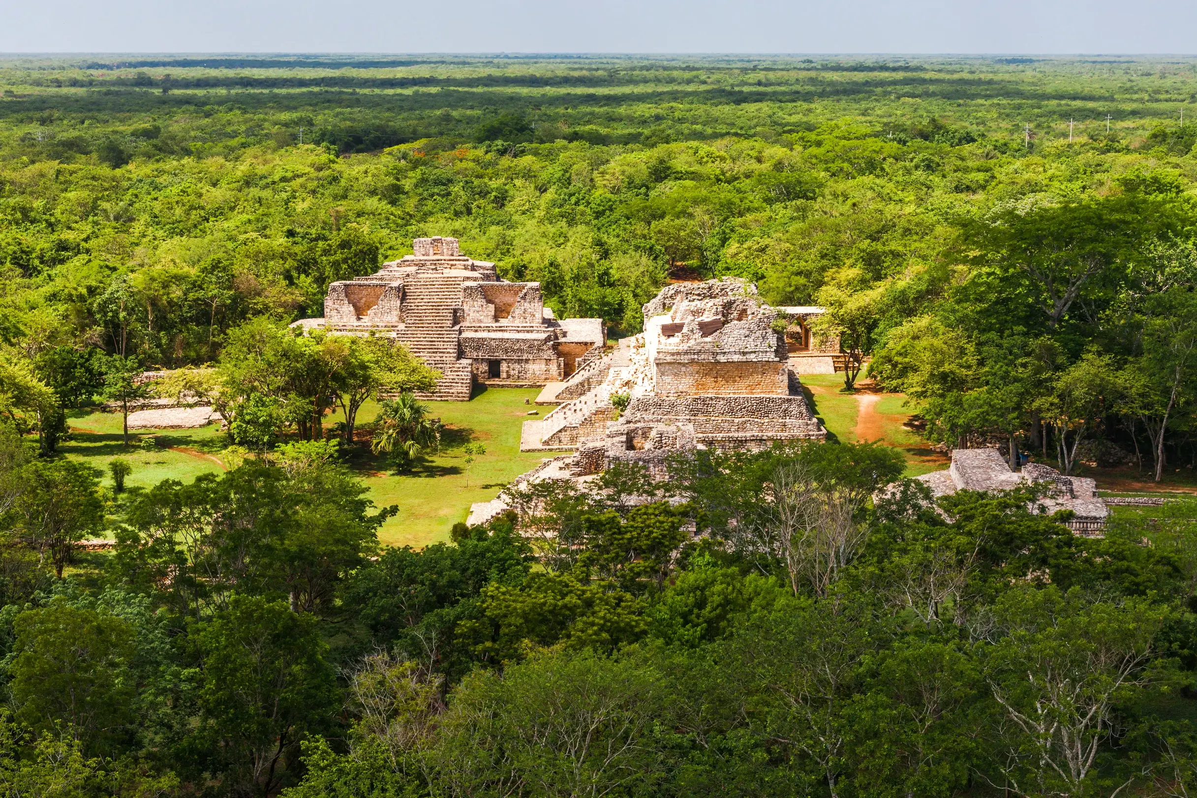 Luftaufnahme der Maya-Ruinen von Ek Balam, deren alte Steinpyramiden aus dem dichten grünen Dschungel Yucatans ragen.