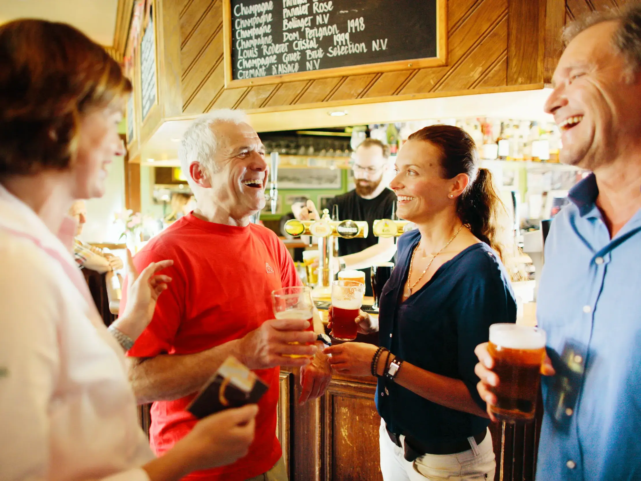 Eine Studiosus Reisegruppe unterhält sich angeregt bei einem Pint Bier an der Theke eines traditionellen walisischen Pubs.