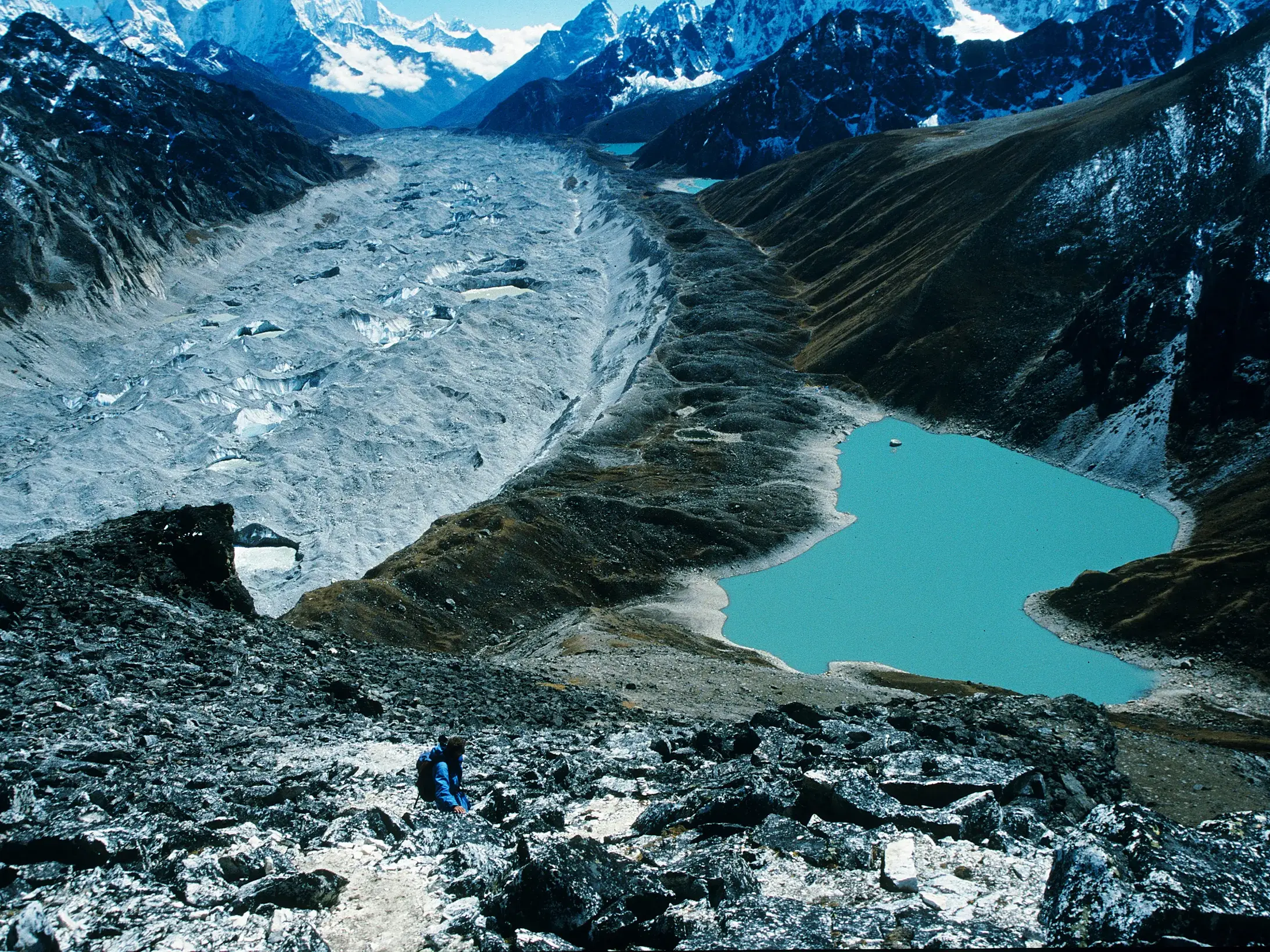 Ein Trekker blickt vom Pass Renjo La auf den türkisen Gokyo-See und den gewaltigen Ngozumpa-Gletscher im Himalaya in Nepal.