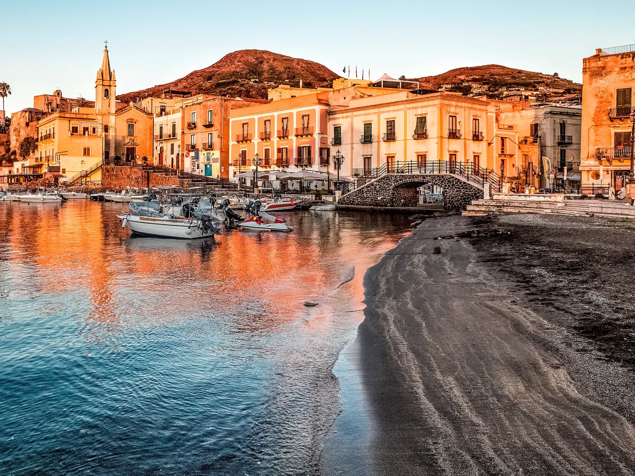Der malerische Hafen Marina Corta in Lipari-Stadt im warmen Abendlicht mit Fischerbooten und historischen Häusern.