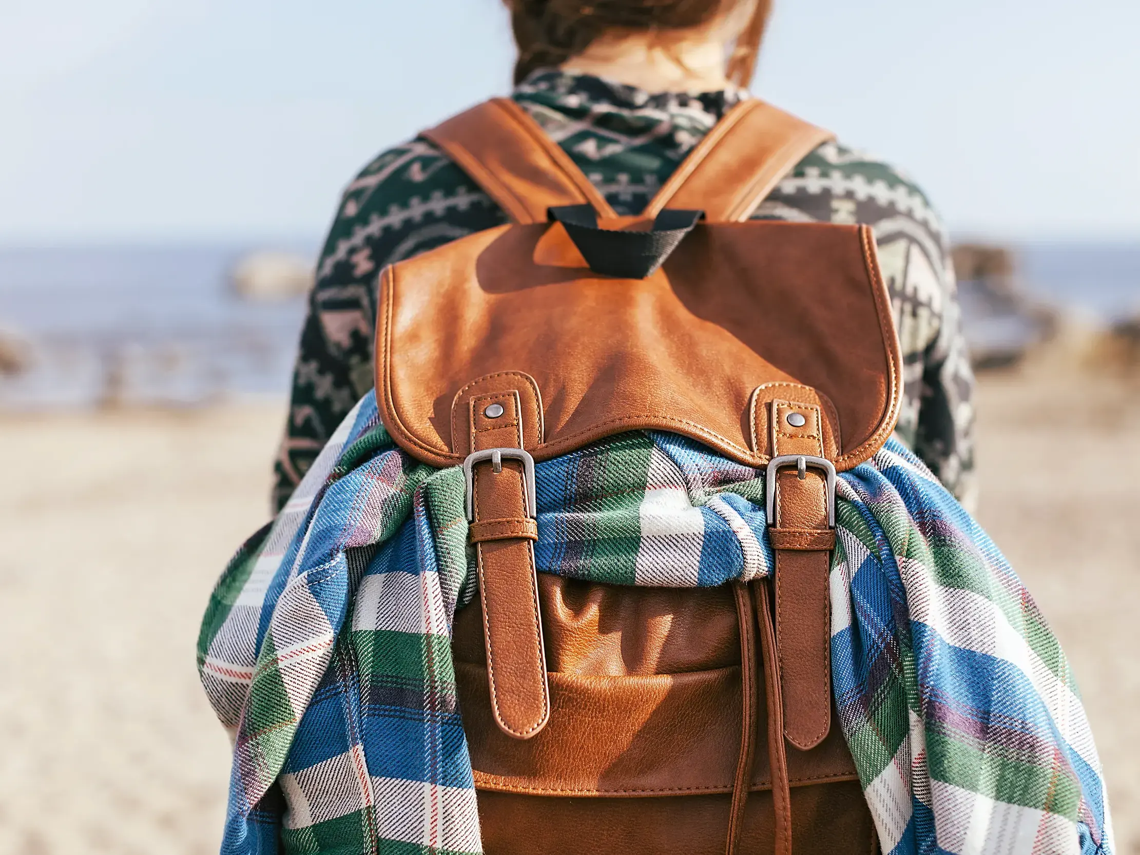 Eine Person mit Wanderrucksack blickt auf einer Wanderreise in Andalusien über den Sandstrand der Costa de la Luz auf das Meer.