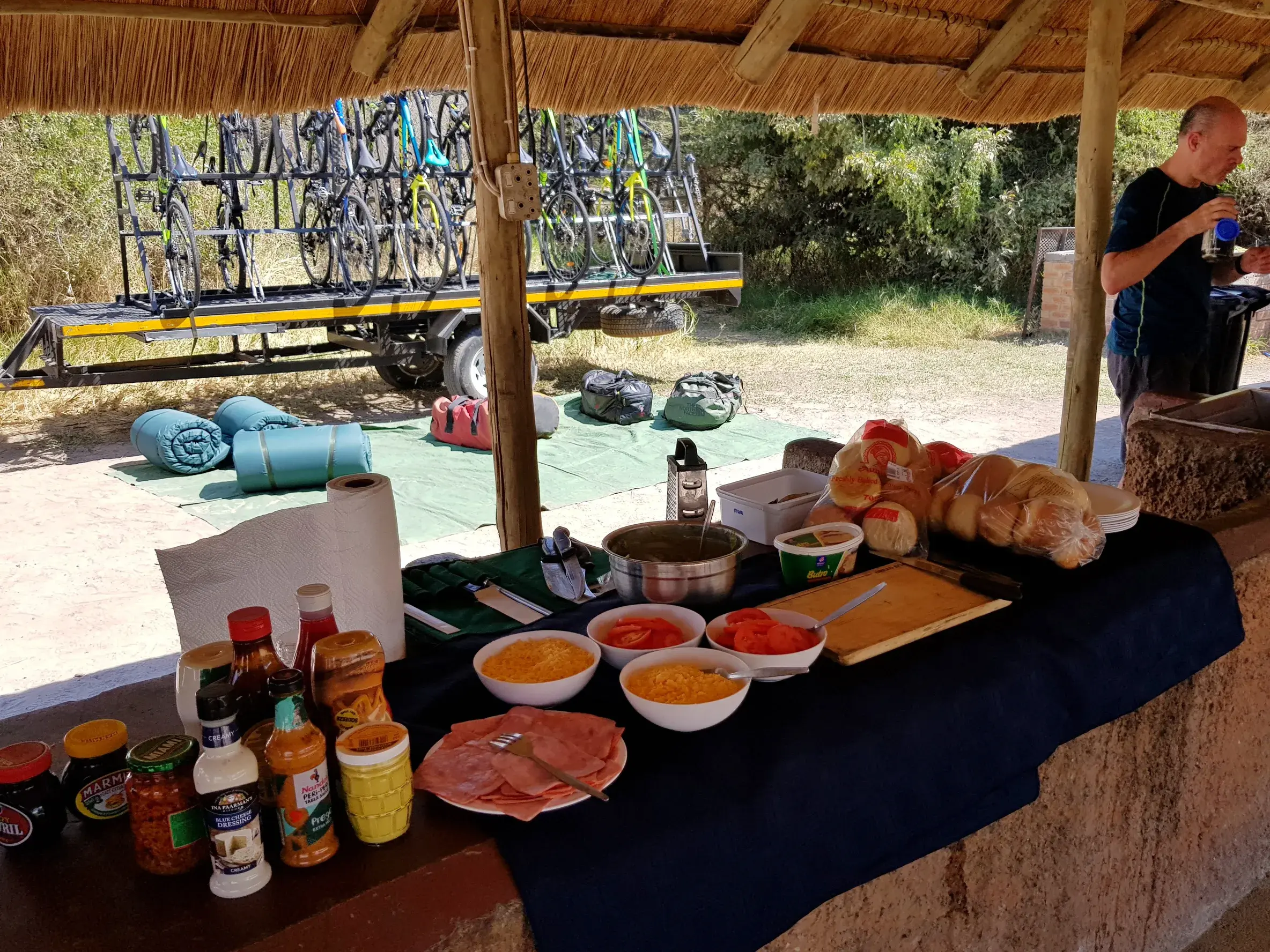 Stärkung bei der Mittagspause einer Rad-Expedition in Afrika mit reichhaltigem Buffet und dem Bike-Transporter im Hintergrund.