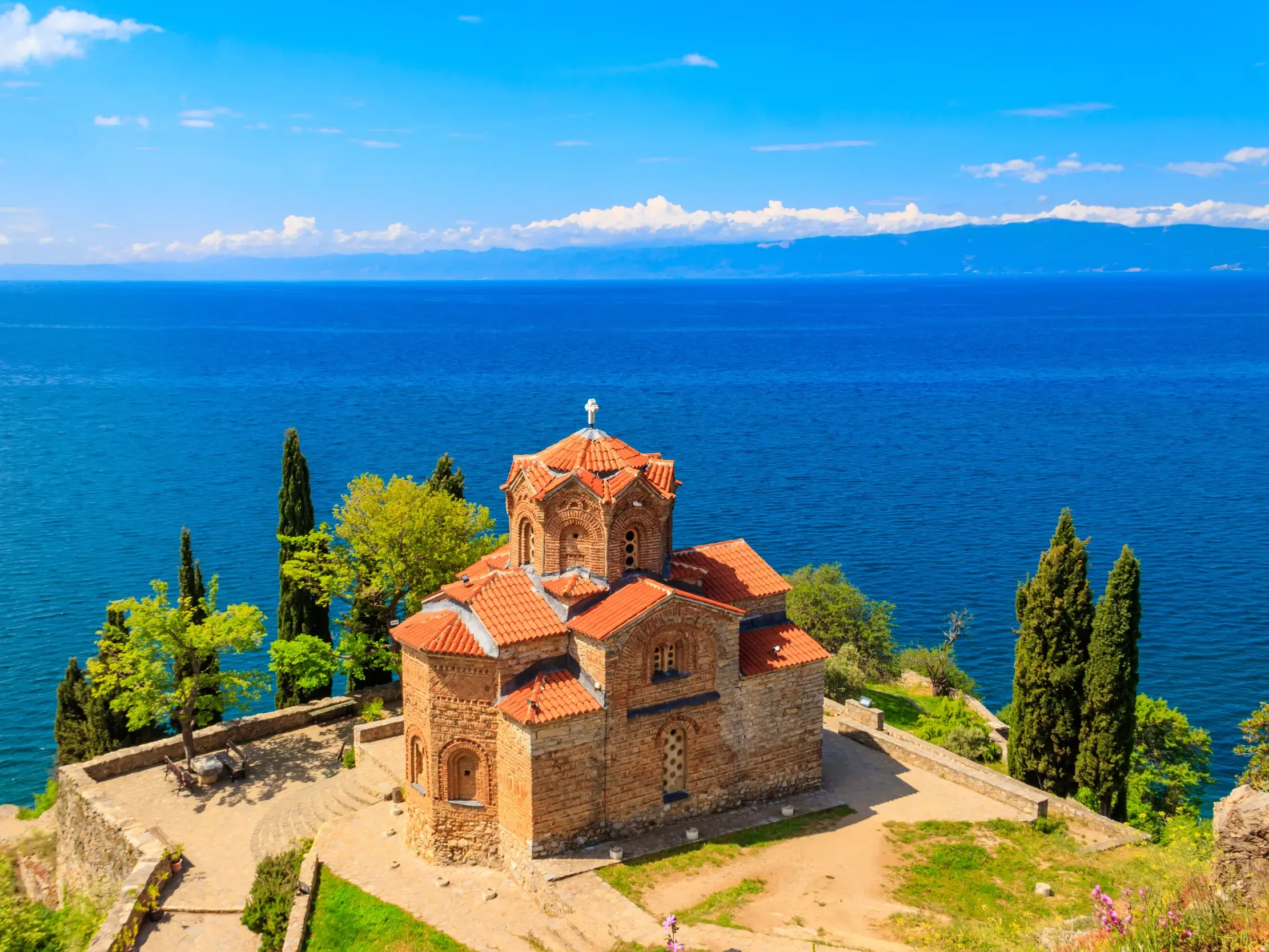 Die orthodoxe Kaneokirche in Ohrid auf einem Felsvorsprung über dem leuchtend blauen Ohrid-See in Nordmazedonien.