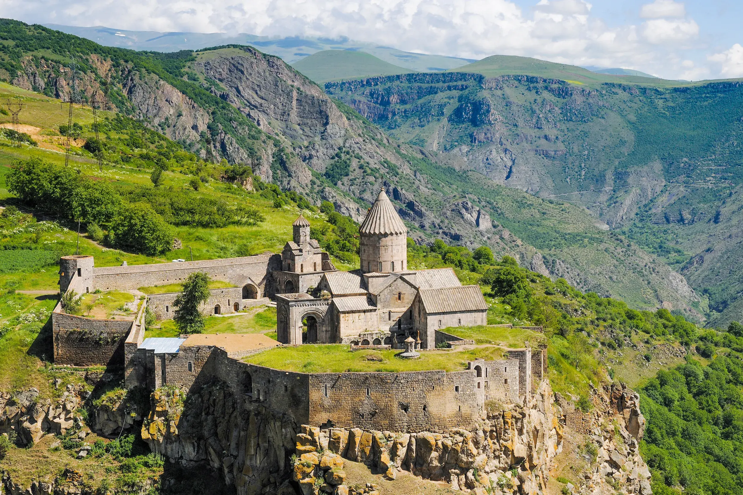 Panoramablick auf das historische Kloster Tatev auf einer Klippe, umgeben von der weiten, grünen Vorotan-Schlucht in Armenien.