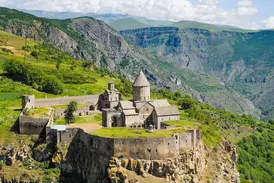 Panoramablick auf das historische Kloster Tatev auf einer Klippe, umgeben von der weiten, grünen Vorotan-Schlucht in Armenien.