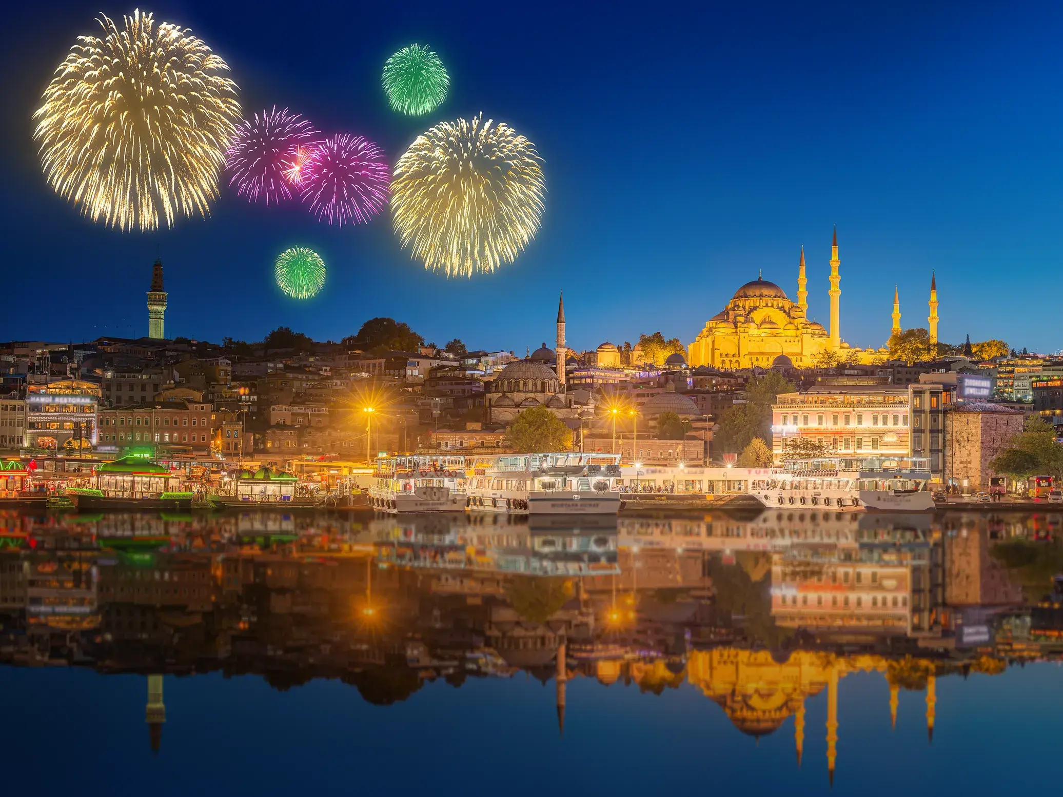 Buntes Silvester-Feuerwerk über Istanbul mit Blick auf die beleuchtete Süleyman-Moschee, die sich im Goldenen Horn spiegelt.
