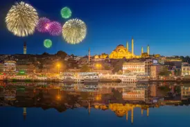 Buntes Silvester-Feuerwerk über Istanbul mit Blick auf die beleuchtete Süleyman-Moschee, die sich im Goldenen Horn spiegelt.