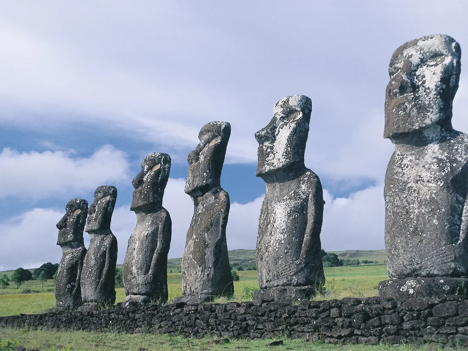 Die eindrucksvollen Moai-Statuen von Ahu Tongariki stehen aufgereiht und blicken über die grüne Vulkanlandschaft der Osterinsel.