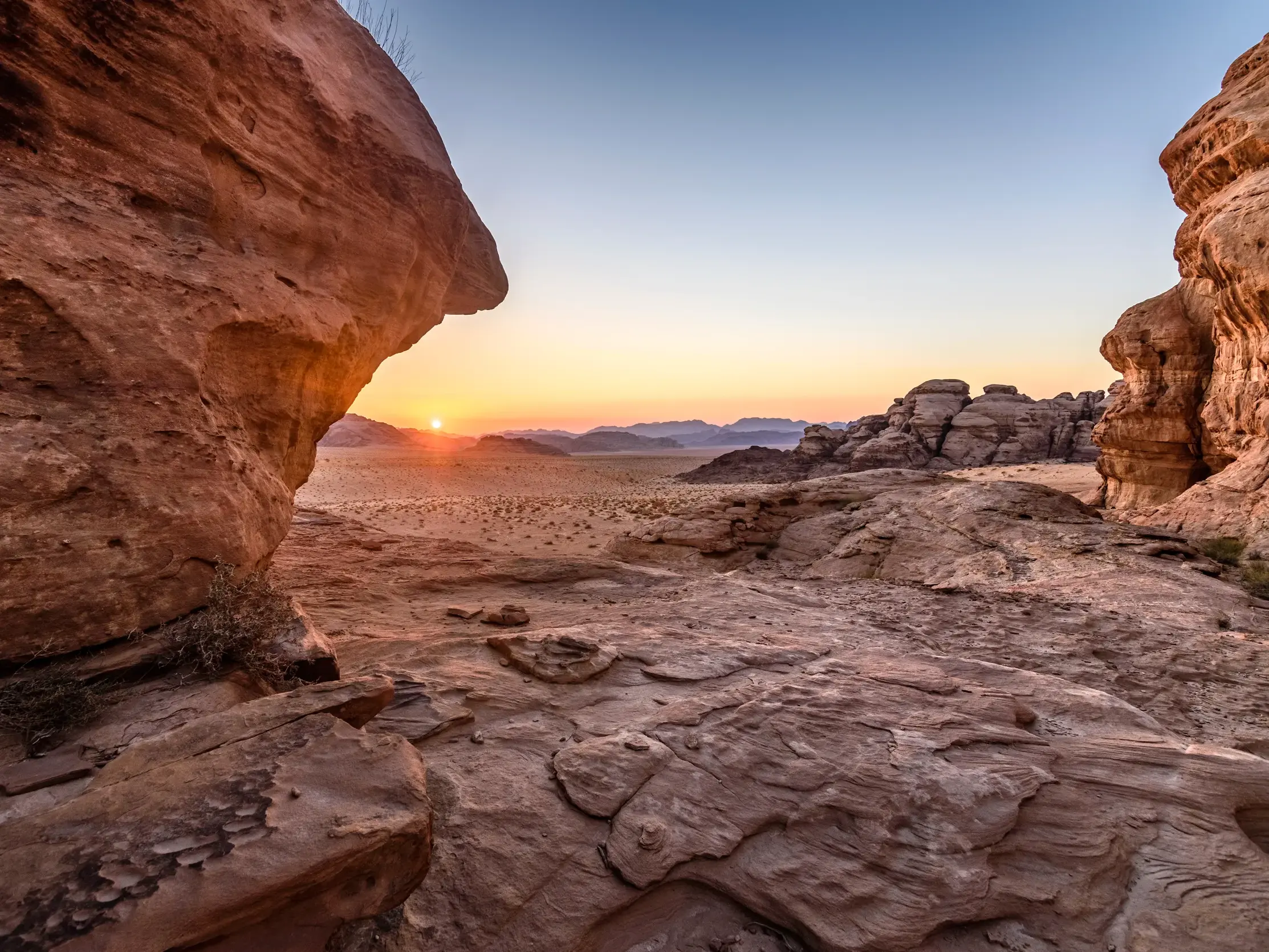 Die Sonne geht über dem weiten Wadi Rum in Jordanien unter und taucht die beeindruckenden roten Felsen der Wüste in goldenes Licht.