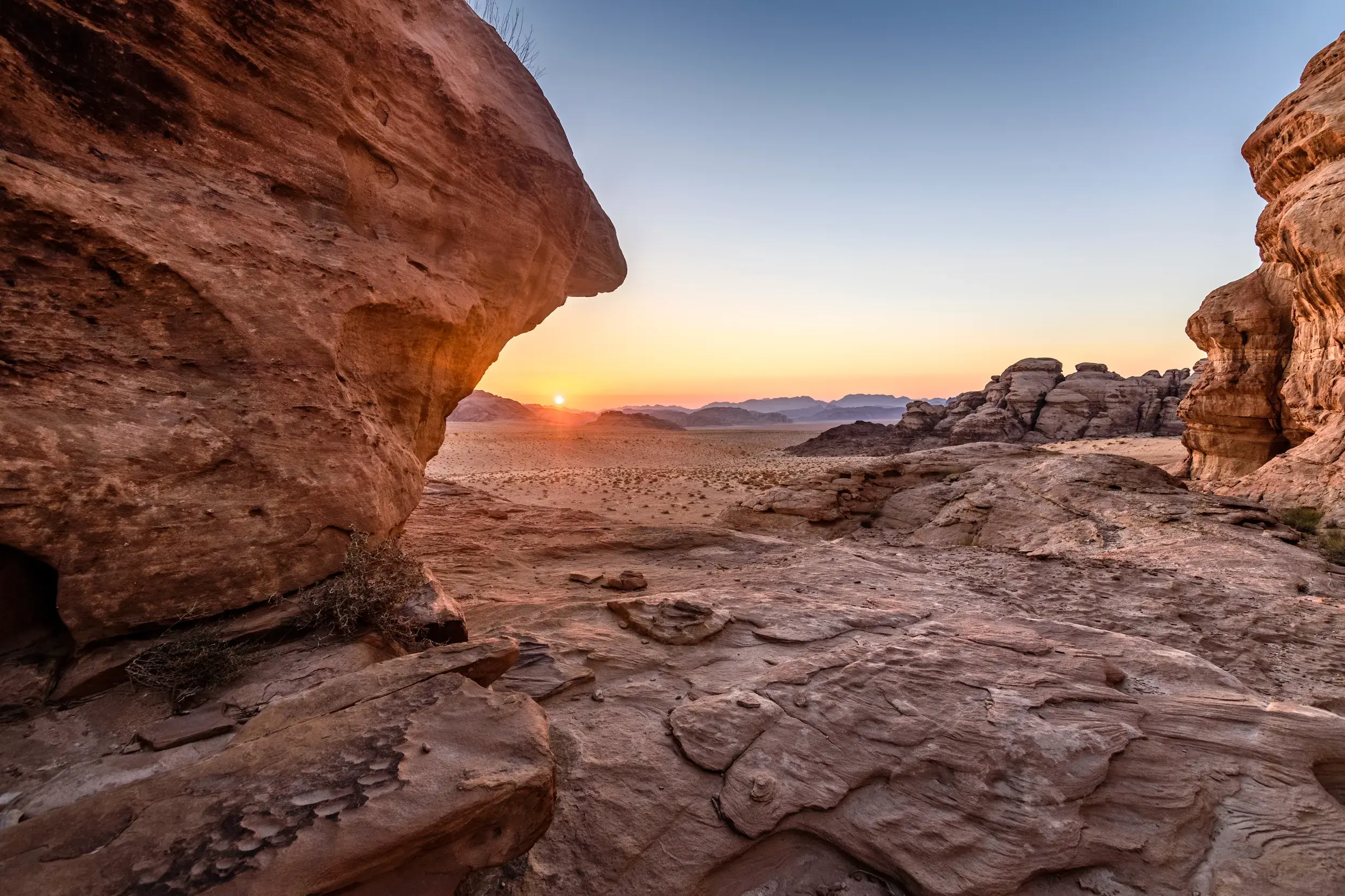 Die Sonne geht über dem weiten Wadi Rum in Jordanien unter und taucht die beeindruckenden roten Felsen der Wüste in goldenes Licht.
