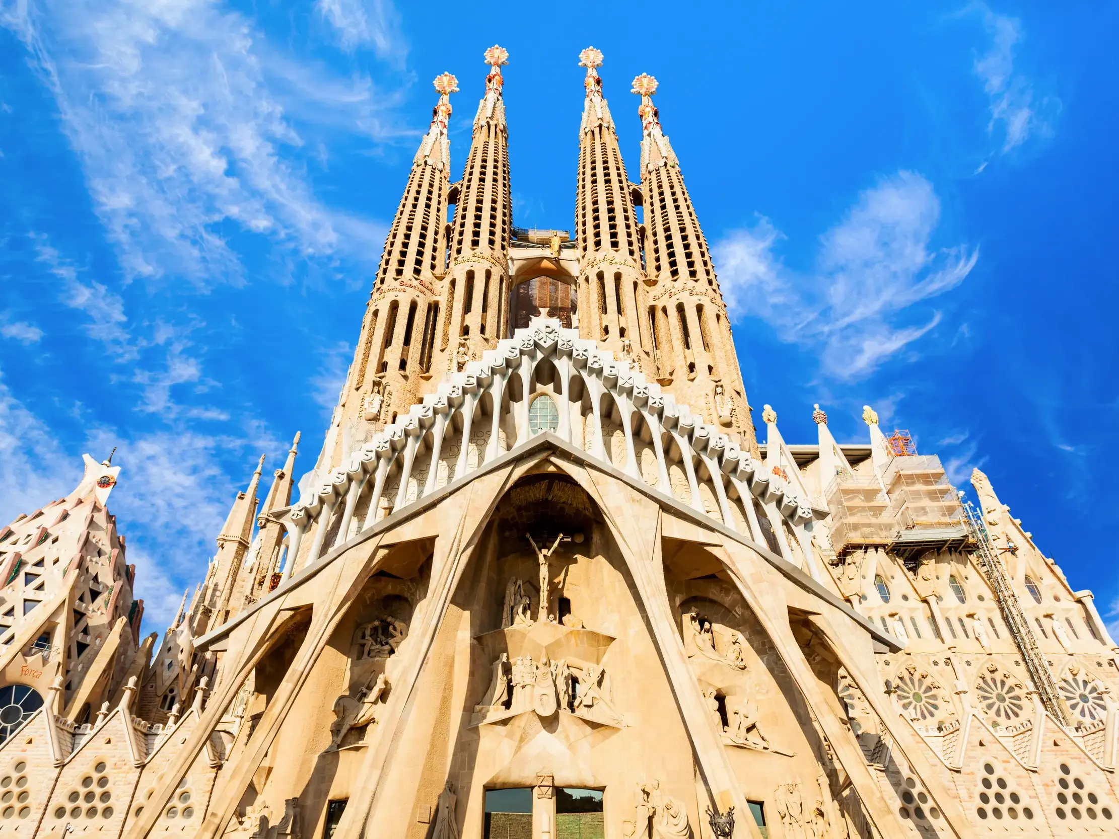 Die beeindruckende Fassade und die markanten Türme von Antoni Gaudís La Sagrada Família in Barcelona bei Sonnenschein.