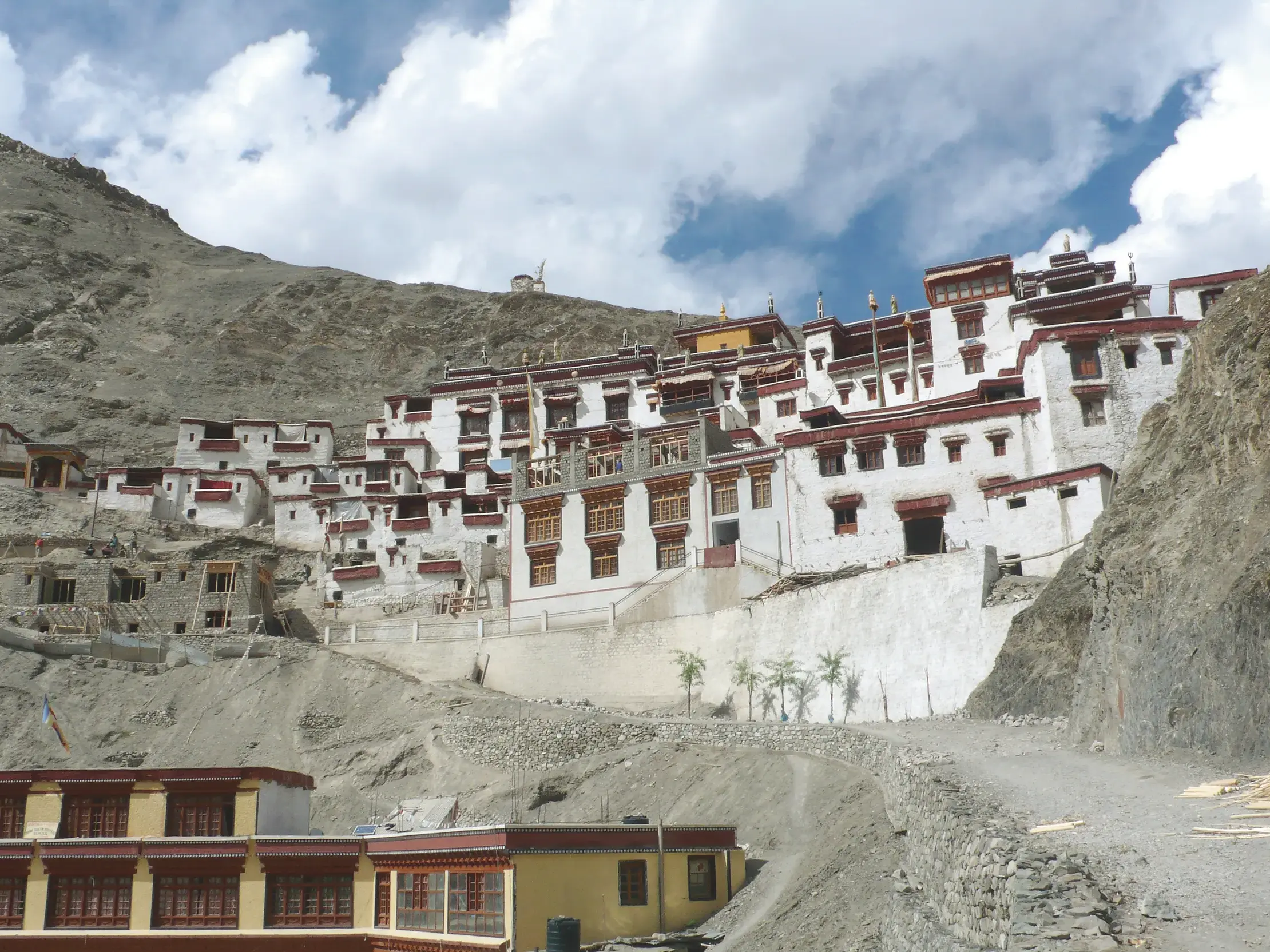 Das terrassenförmig erbaute Rizong-Kloster in Ladakh mit seinen weißen Mauern an einem kargen Berghang unter wolkigem Himmel.