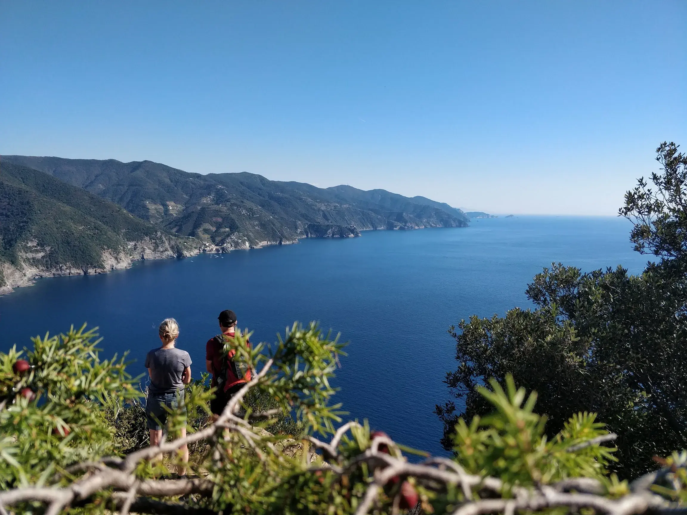 Ein Wanderpaar macht bei einer Trekking-Tour Pause mit Blick auf die spektakuläre Steilküste der Cinque Terre.