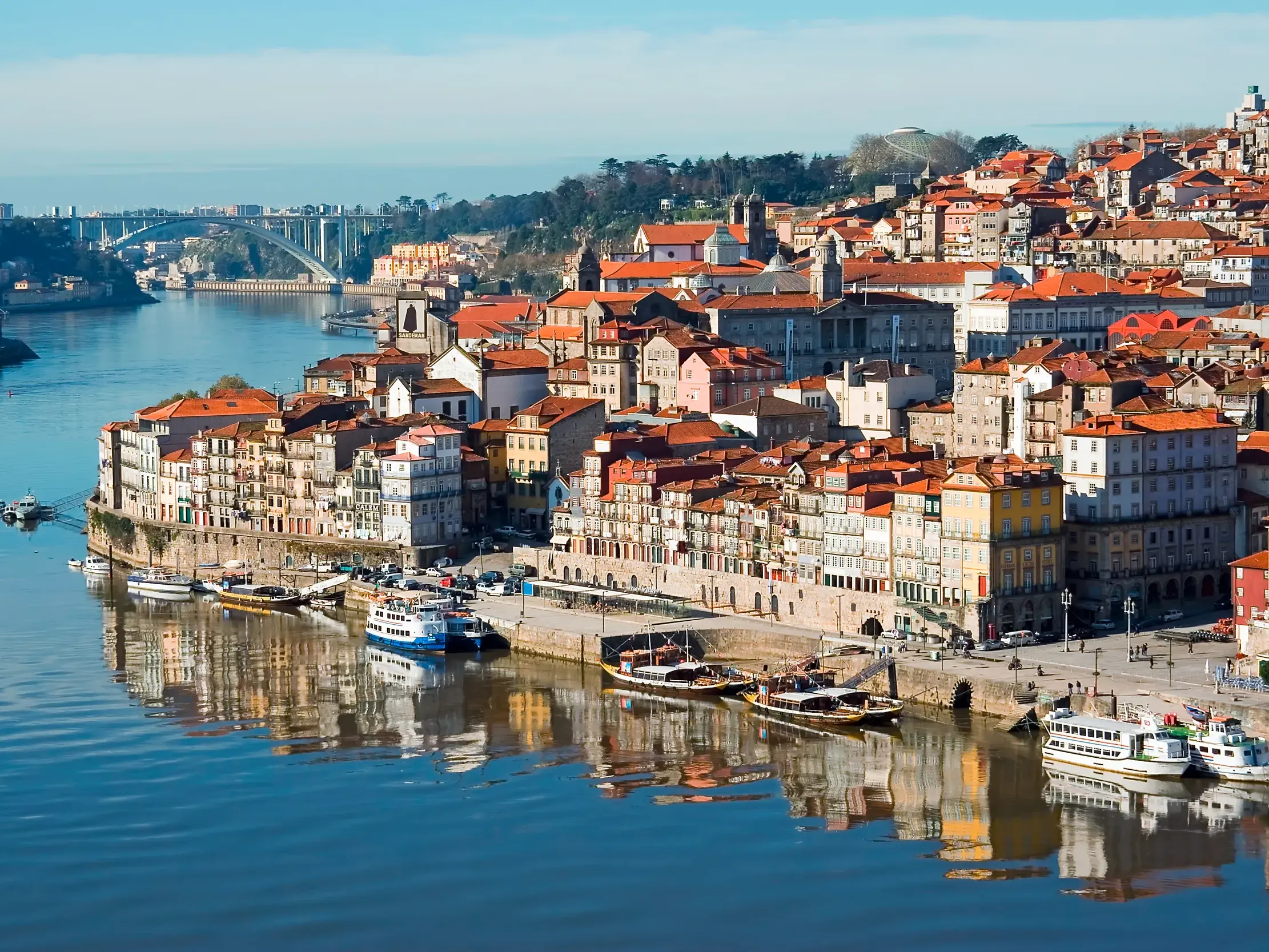 Die farbenfrohen Häuser des historischen Ribeira-Viertels in Porto spiegeln sich im sonnigen Wasser des Flusses Douro.