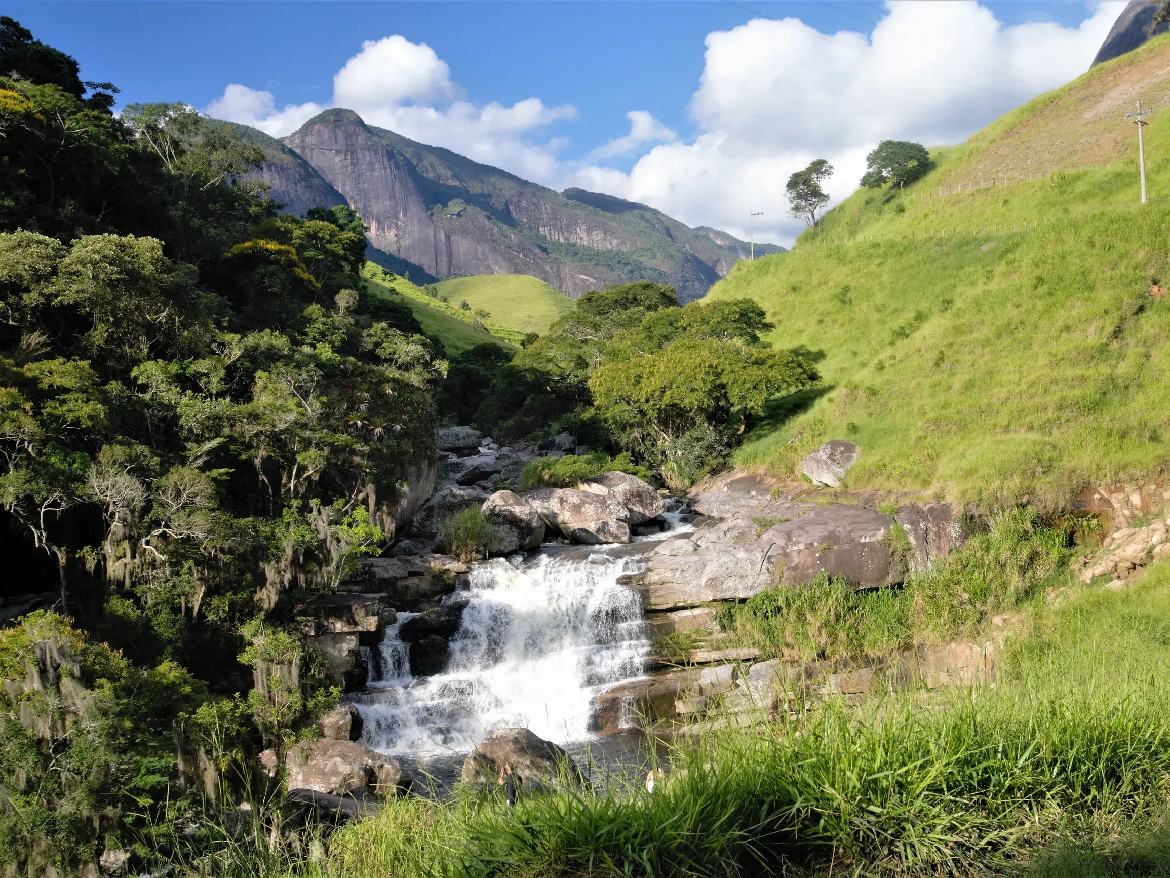 Rauschender Wasserfall in einer üppig grünen Berglandschaft während einer Trekkingreise durch Brasiliens Atlantischen Regenwald.