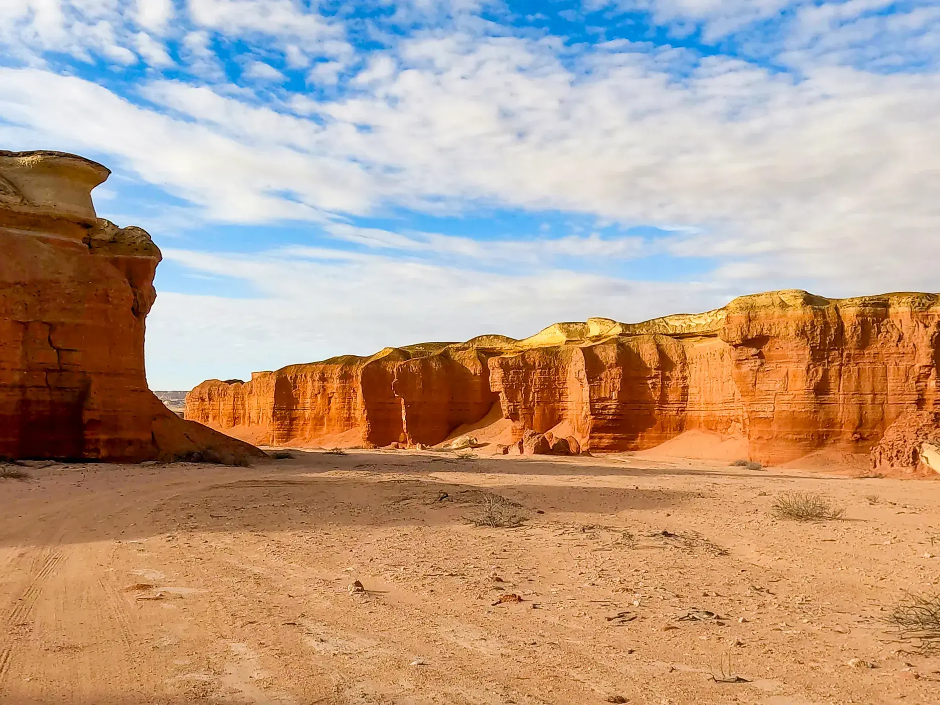 Rötliche, vom Wind geformte Sandsteintürme ragen im weiten Colinas Canyon in Angola in den leicht bewölkten Himmel.