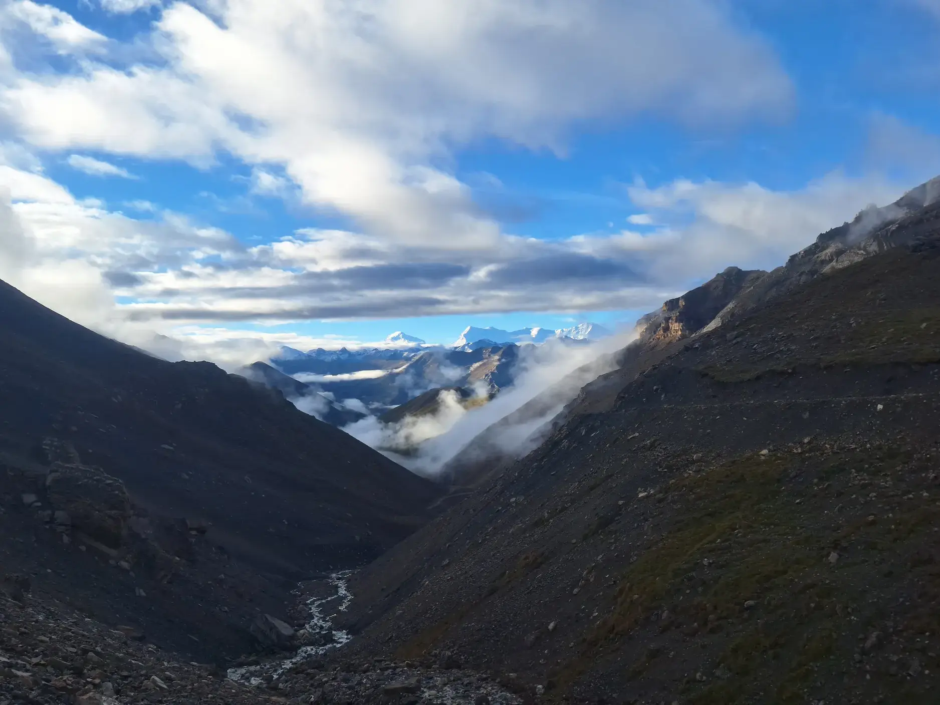 Atemberaubender Blick beim Trekking im Dolpo auf ein tiefes Tal mit Flusslauf und die schneebedeckten Gipfel des Himalaya.