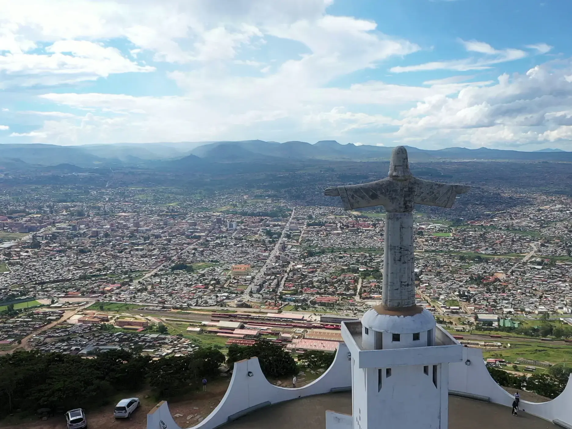 Panoramablick von der Cristo Rei Christusstatue über die weitläufige Stadt Lubango in Angola bis zur fernen Bergkette am Horizont.